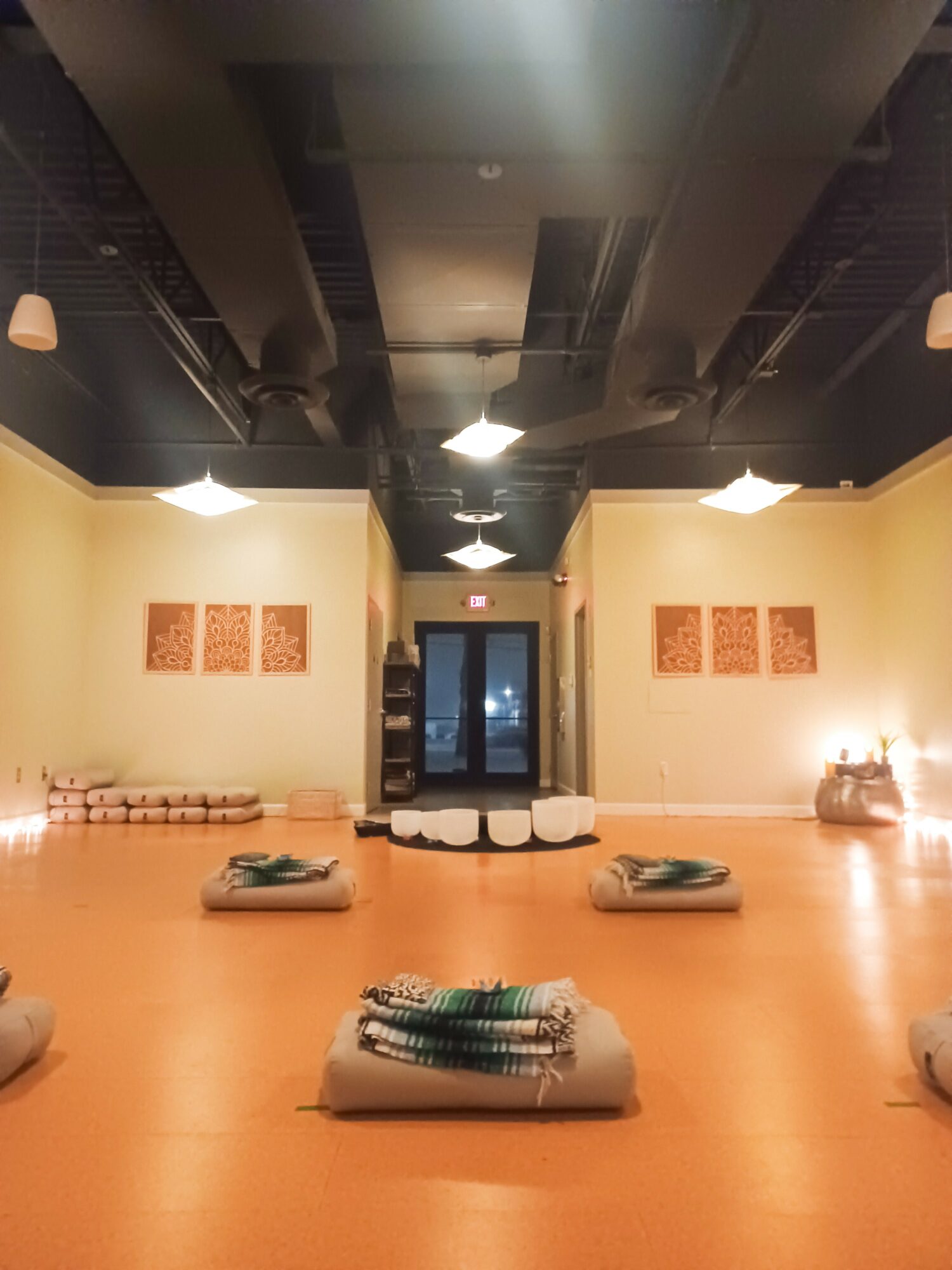 Empty room with a polished floor, wall art, and a door at the back, illuminated by ceiling lights.