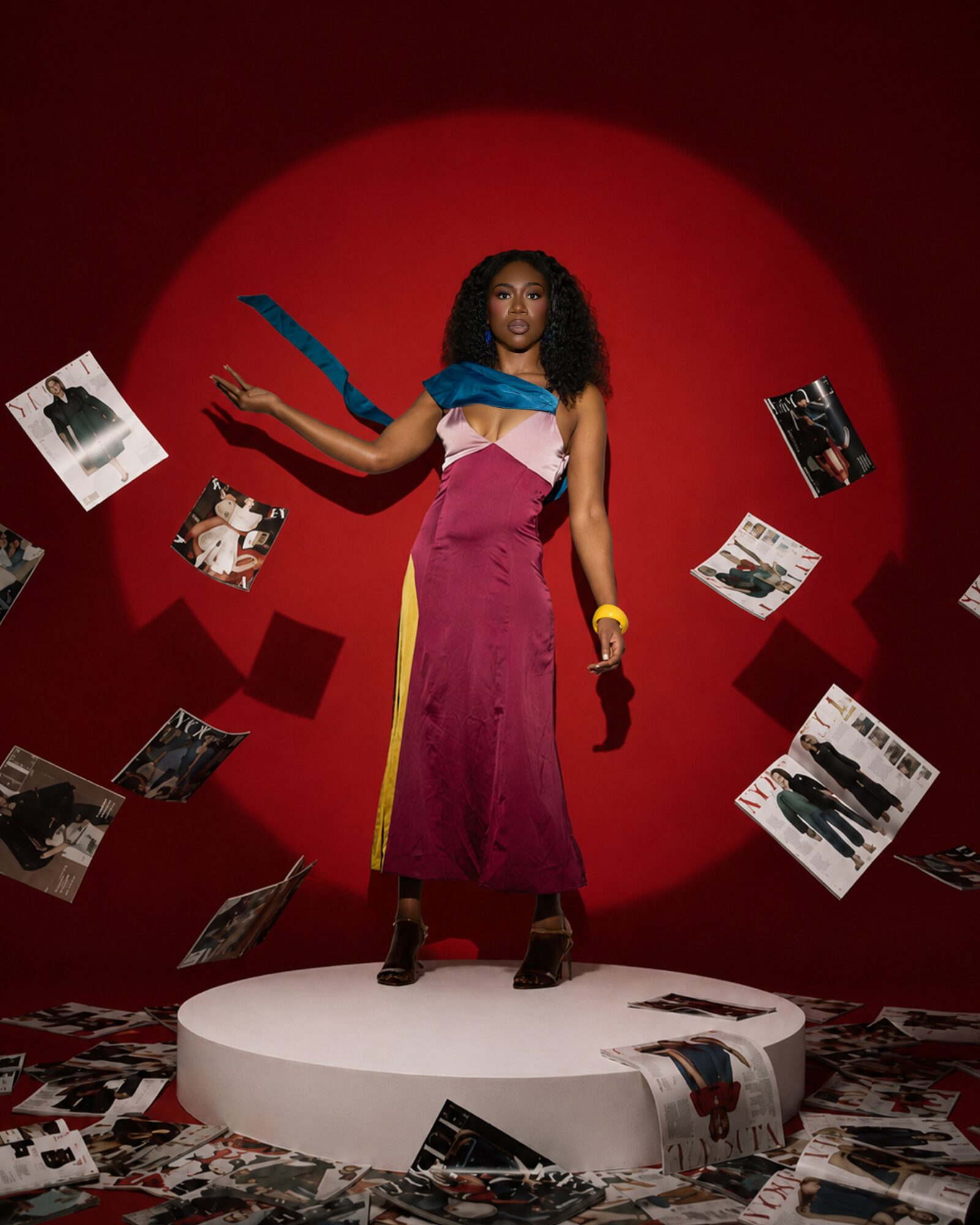 Woman standing on a white circular platform with photos floating around her, red background, dramatic lighting.