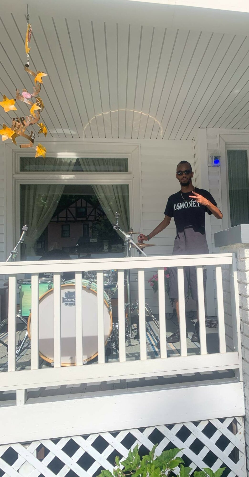 Person standing on porch holding a spray wand, with a white railing and house in background.