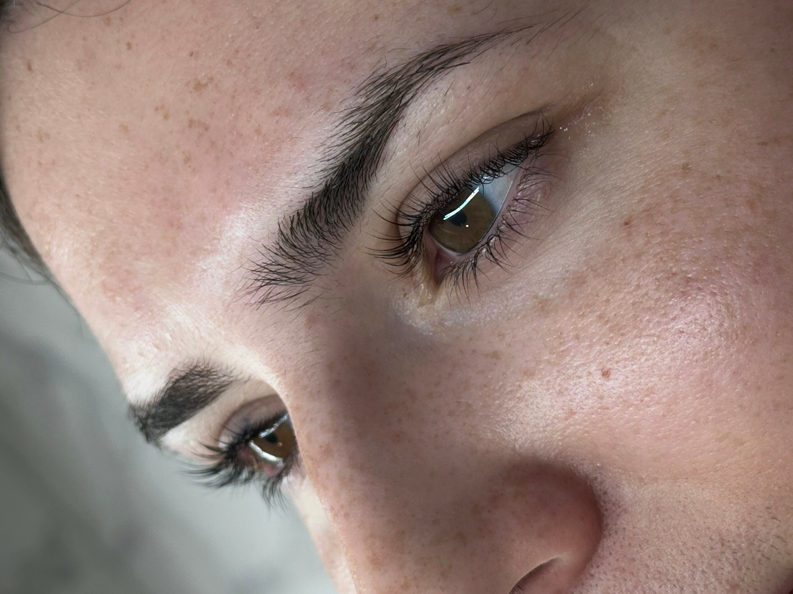 Close-up of a person's face showing eyes, eyebrows, and skin texture with freckles.
