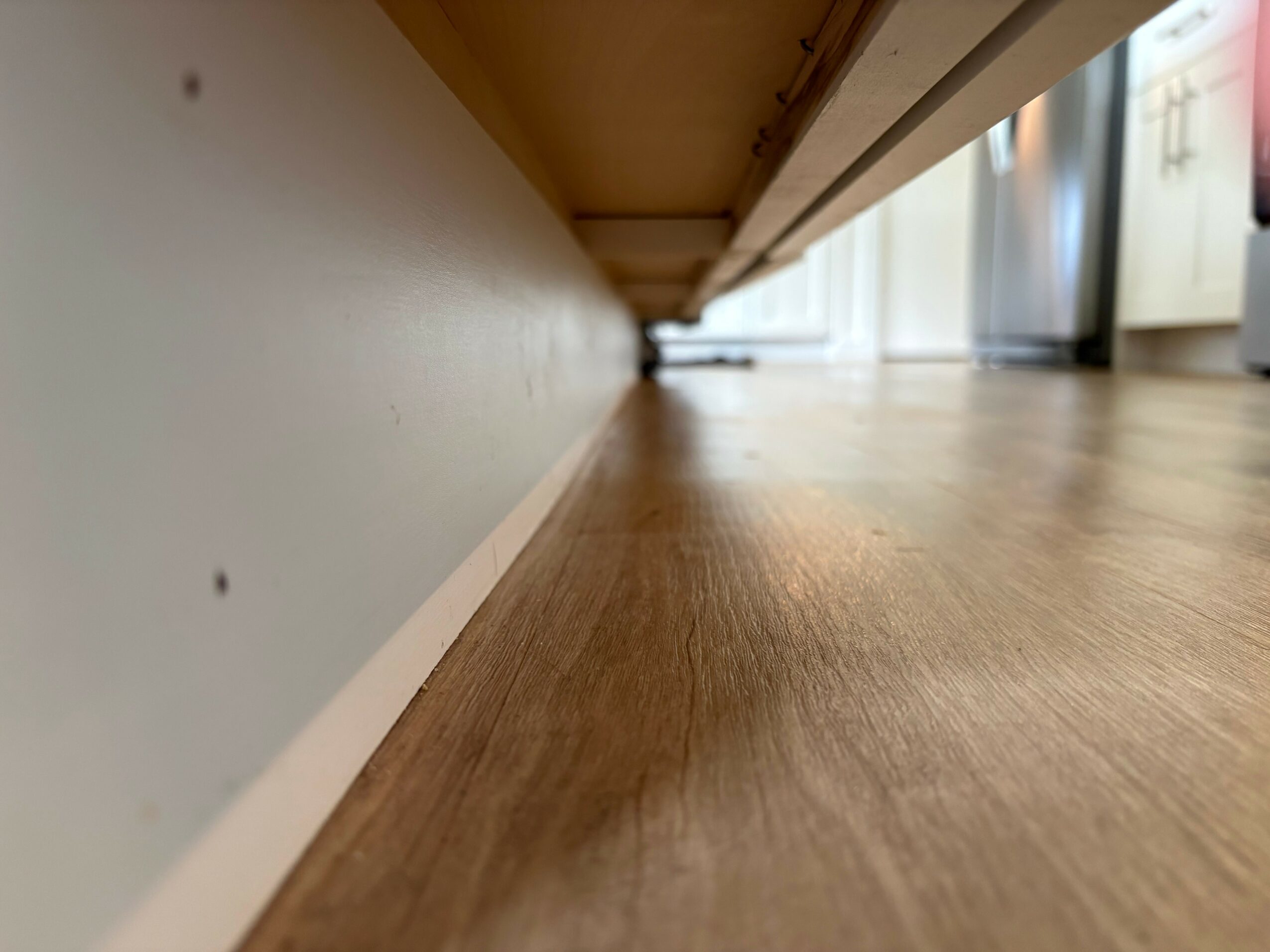 Floor and lower part of a wall with a cabinet above, viewed from a low angle.