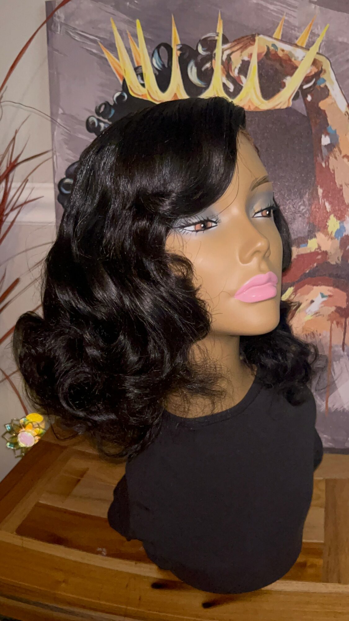 Bust of a woman with wavy black hair, wearing pink lipstick, in front of a colorful background with text.
