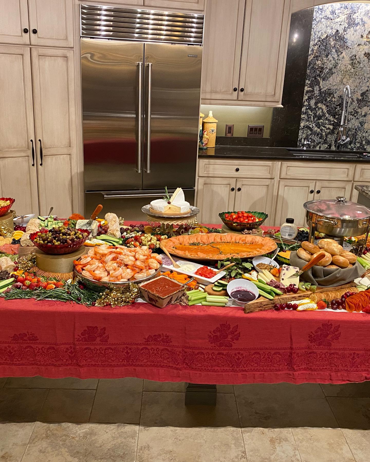 Table with various dishes and bowls in a kitchen with cabinets and a refrigerator in the background.