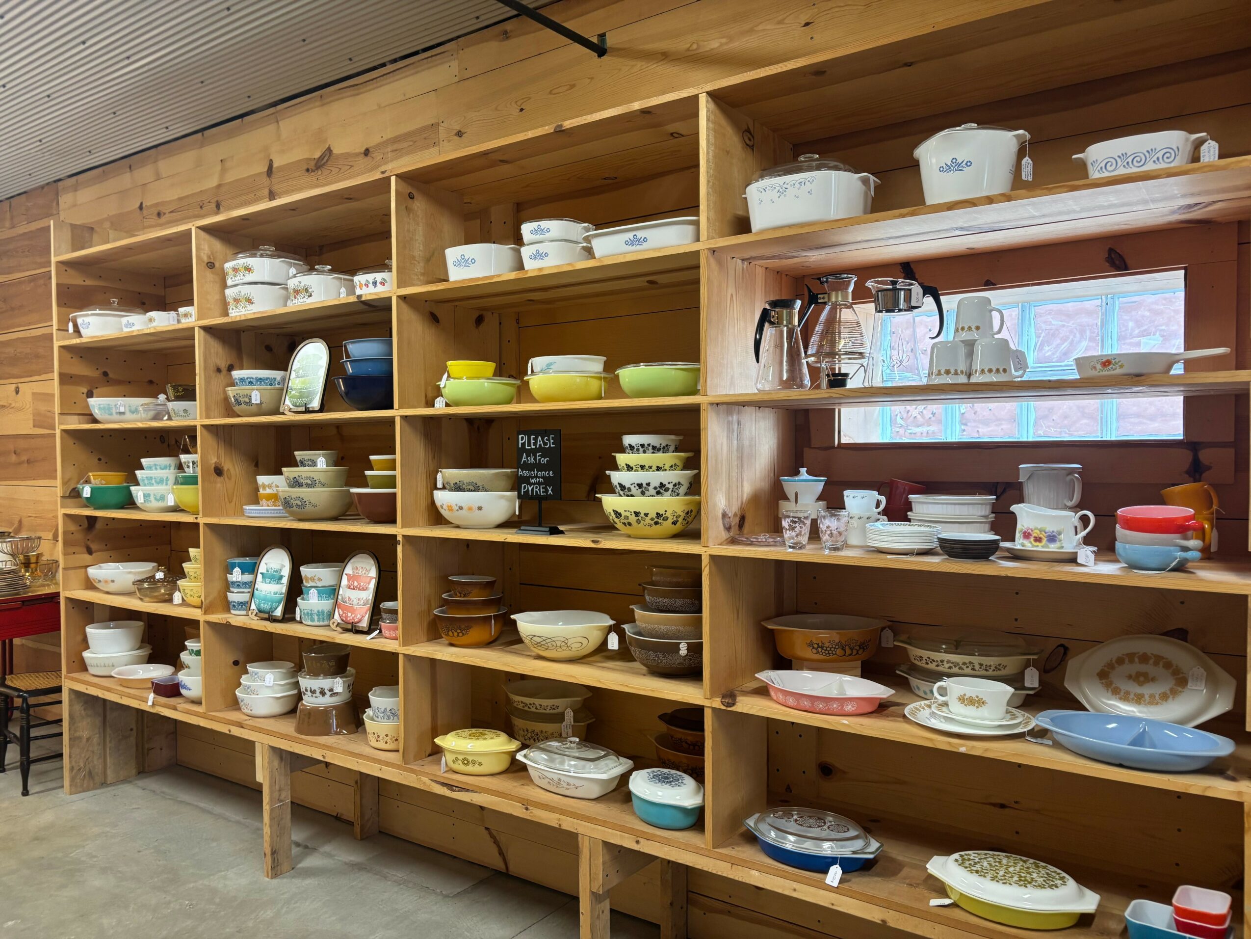 Wooden shelves filled with various bowls, plates, and cups in a store or kitchen setting.