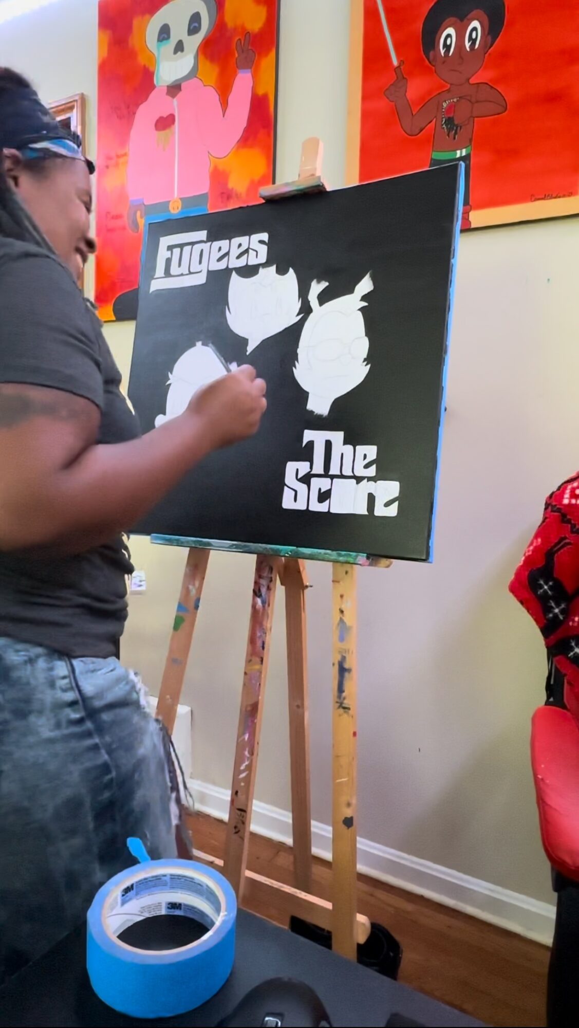 Child painting a black and white silhouette on a canvas with colorful artwork in the background.
