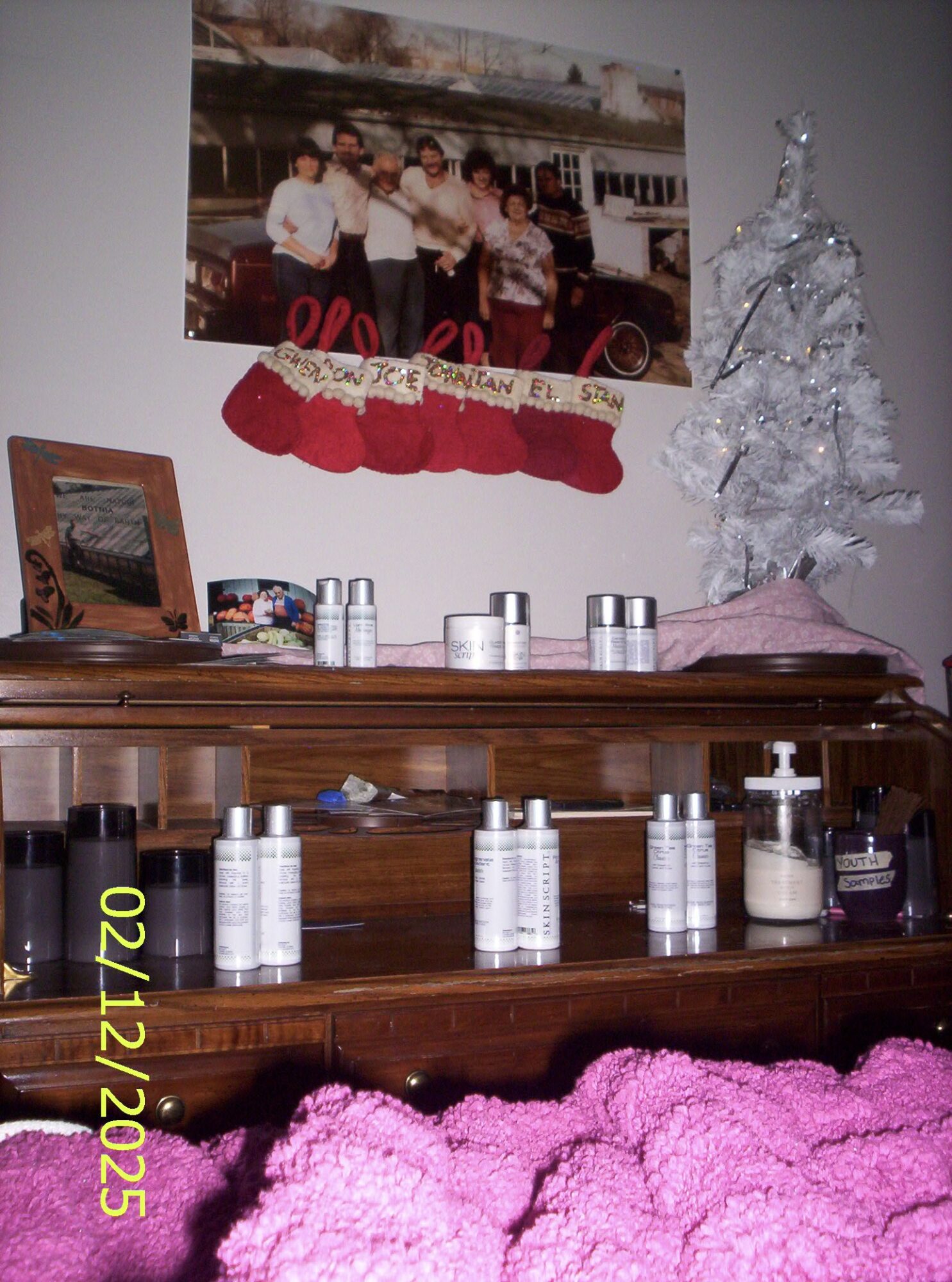 A wooden shelf with bottles, a framed photo, and Christmas decorations including a small white Christmas tree and red stockings.