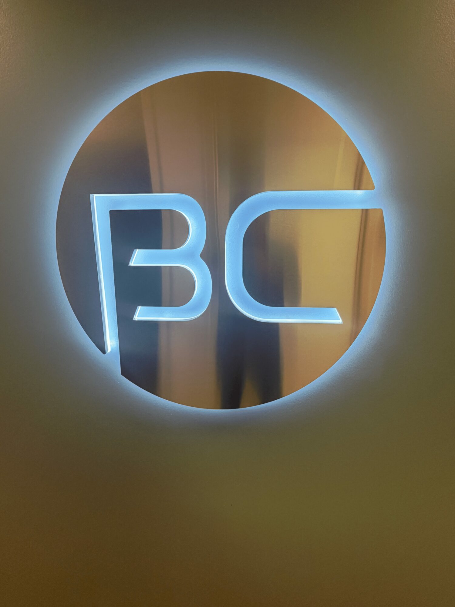 Illuminated circular sign with the letters 'BC' inside, glowing with a blue hue.