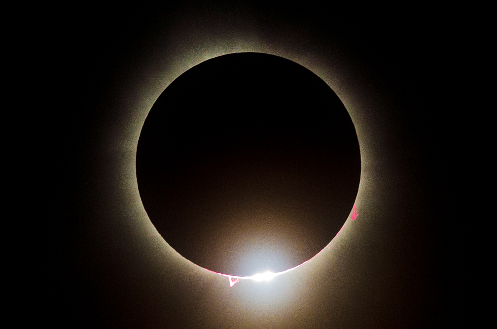 A solar eclipse with the moon covering the sun, creating a dark circle with a bright ring around it.