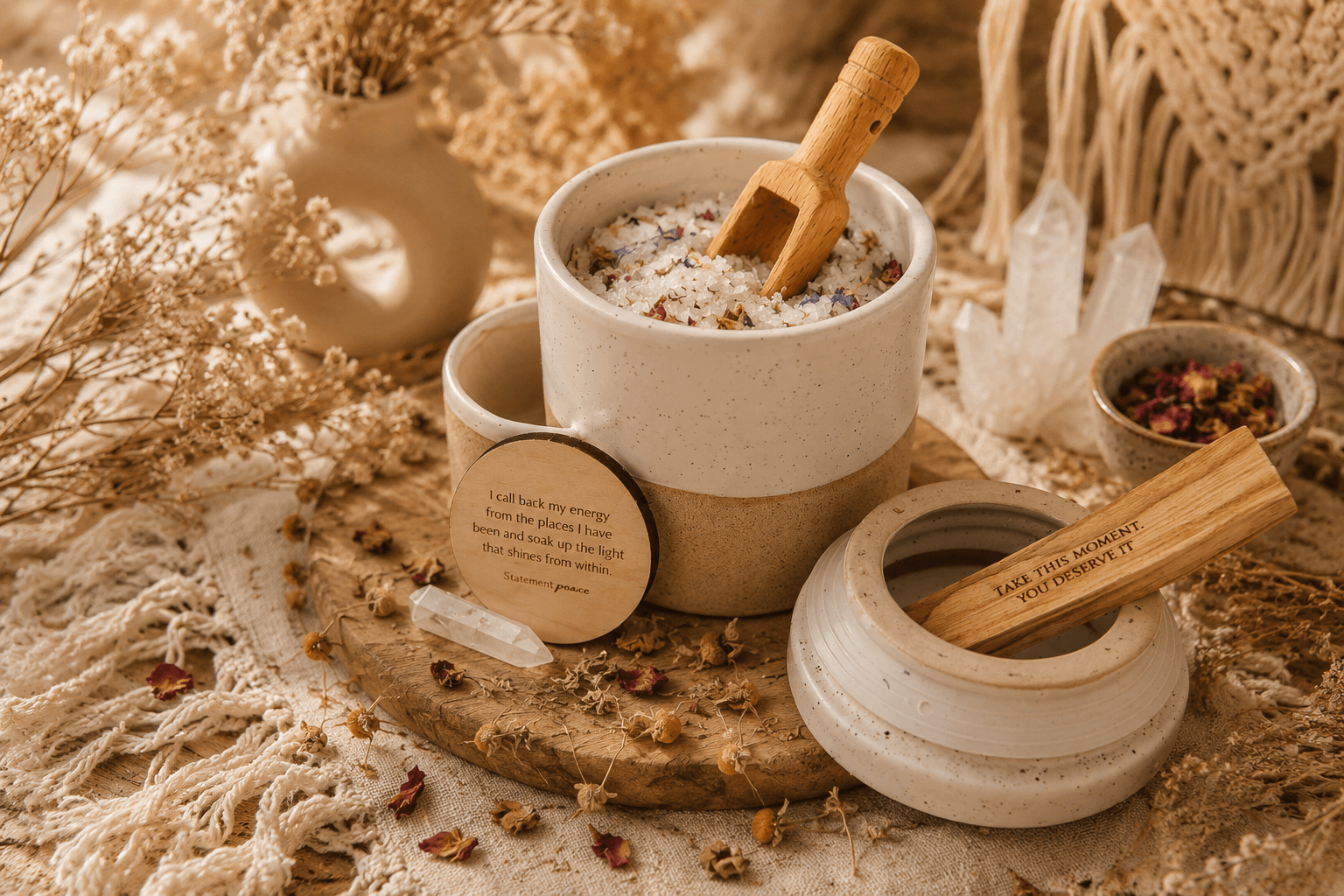 Cream-colored bowl with a wooden spoon, surrounded by small bowls, on a textured surface with dried plants and decorative items