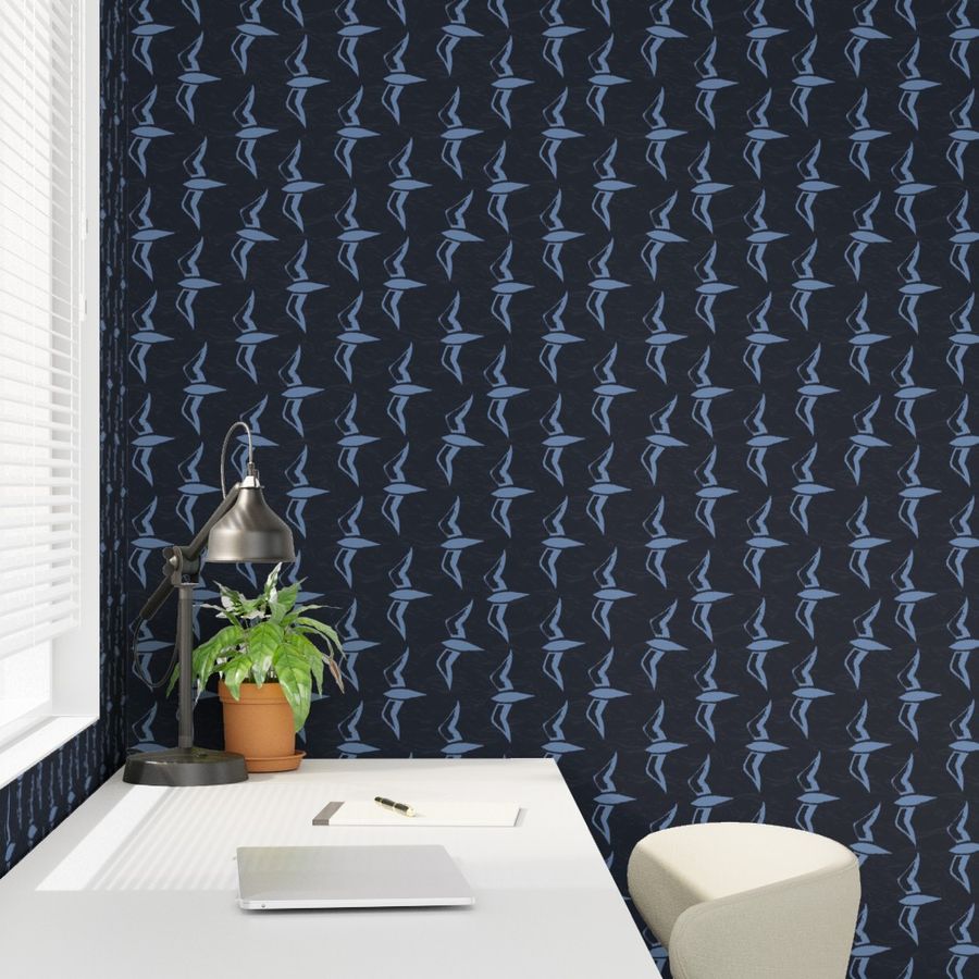 Desk with a lamp, potted plant, and notebook in a room with dark patterned wallpaper.