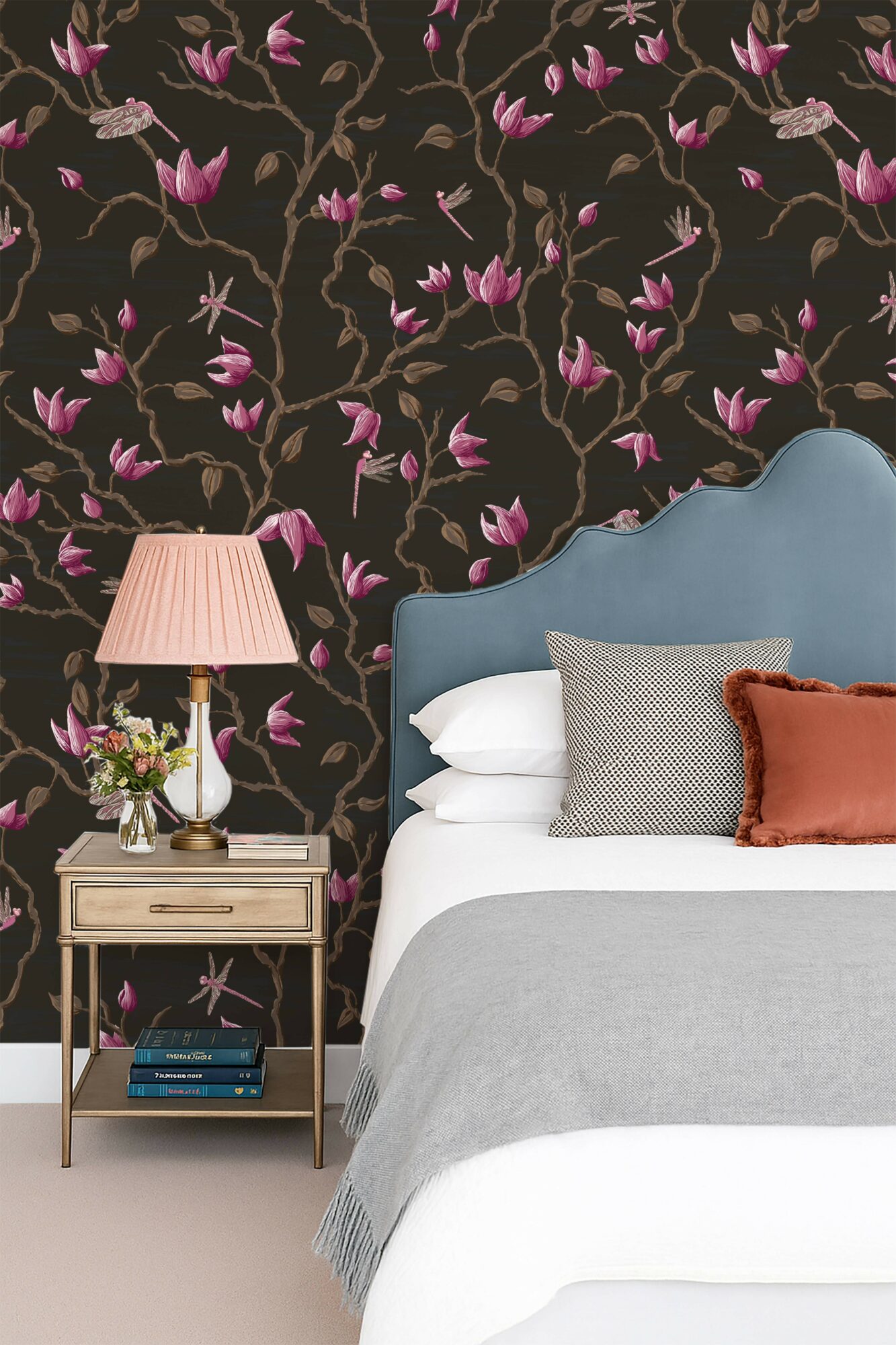 Bedroom with floral wallpaper, blue headboard, bedside table with lamp, and pillows on bed.