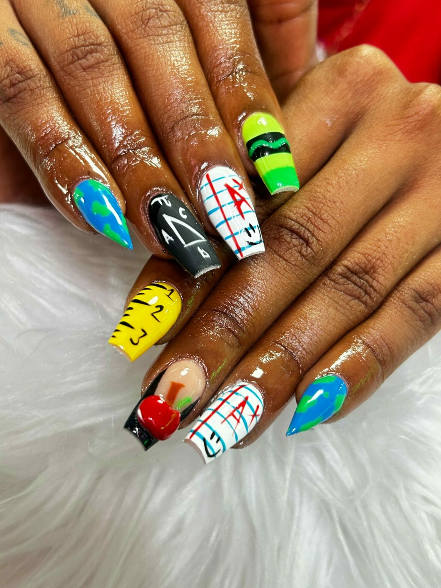Close-up of hands with colorful, patterned nail art on long nails, resting on a white furry surface.