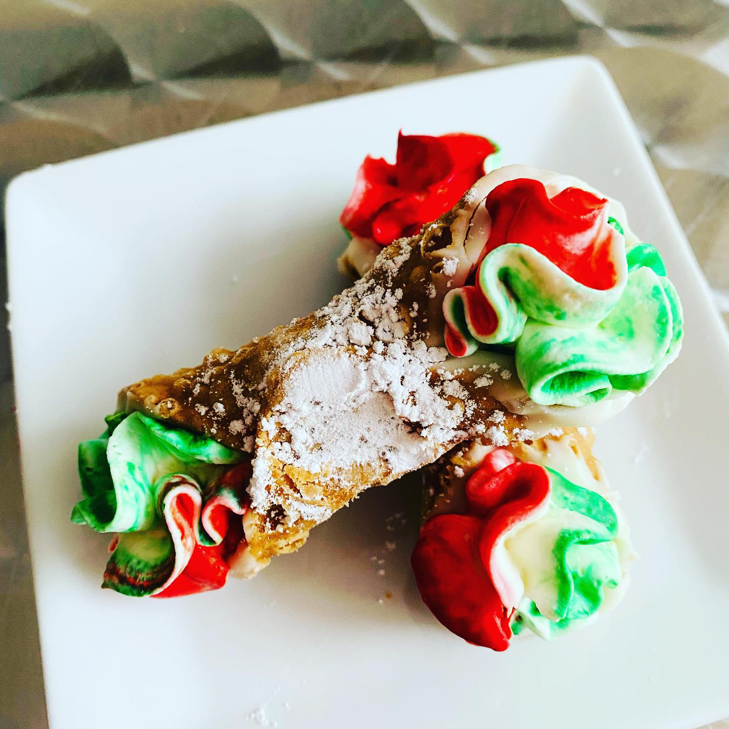 Decorated pastry with red, green, and white icing on a white plate.