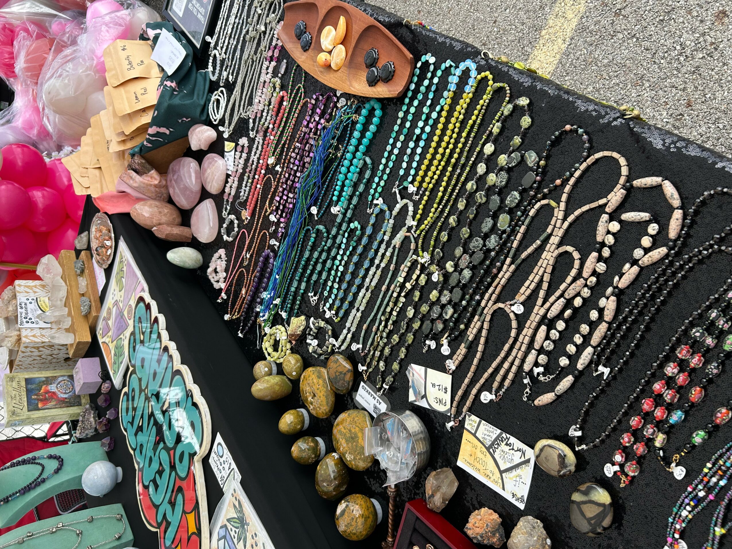 Jewelry and accessories displayed on a table at a market stall, including necklaces, bracelets, and beads.