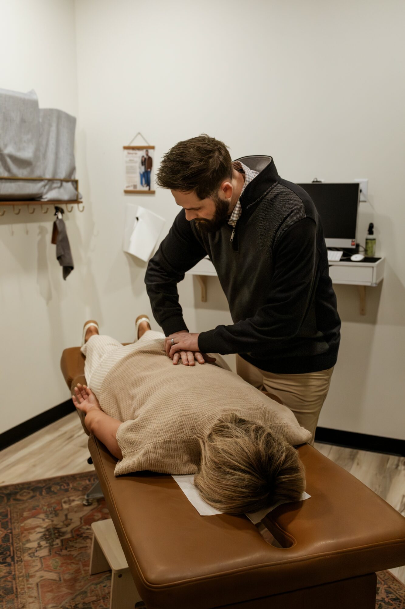 Person performing a medical procedure on a patient lying on a table in a clinical room.