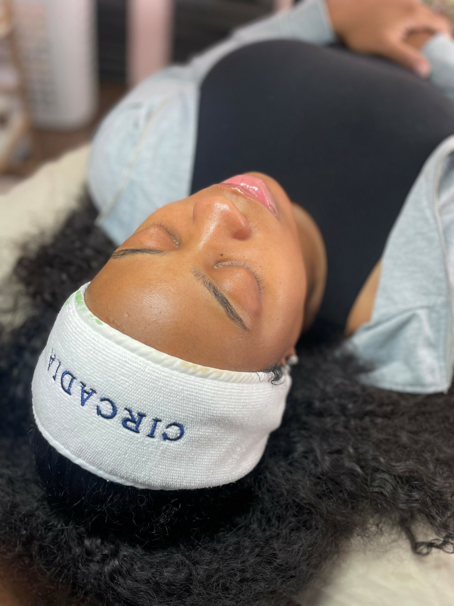 Woman lying down with eyes closed, wearing a white headband with 'CIRCADIA' written on it, in a relaxed setting.