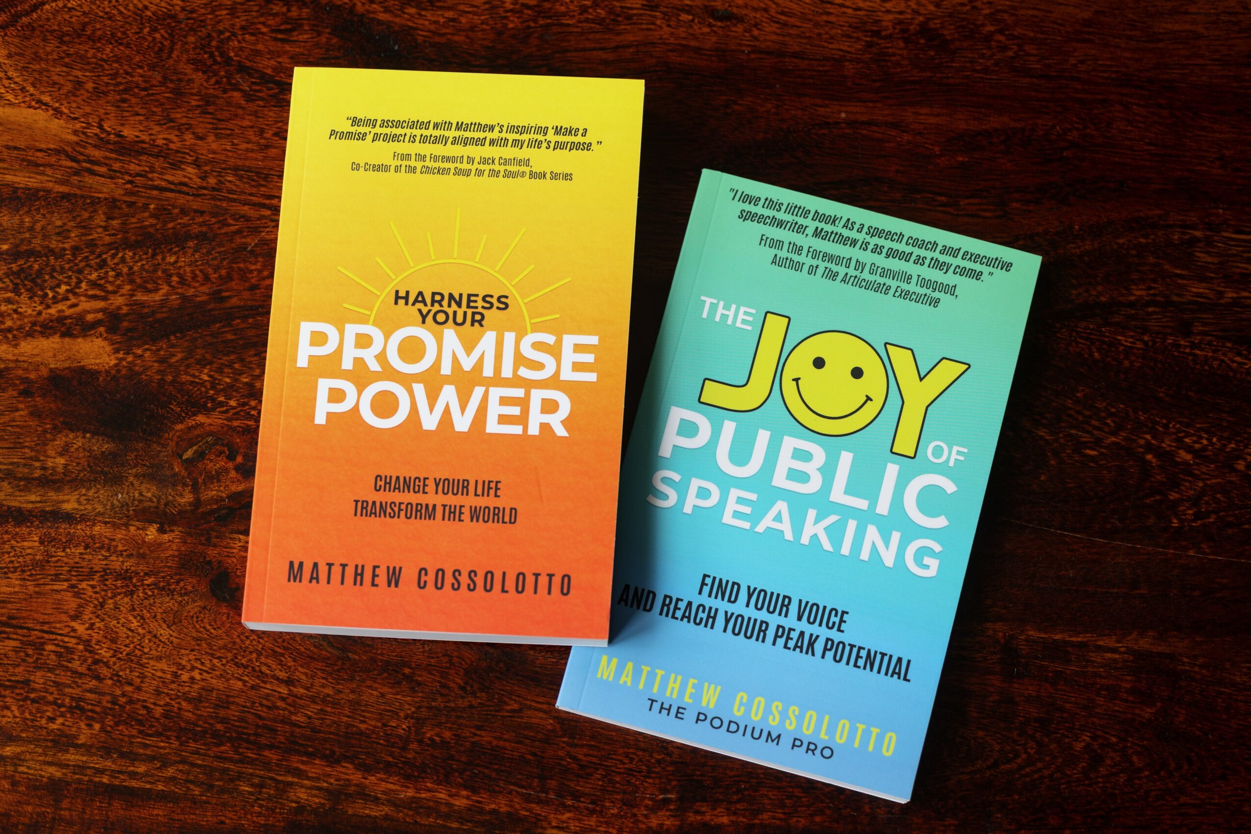 Two colorful flyers on a wooden surface, one yellow and orange, the other blue and green, promoting public speaking and promise power.