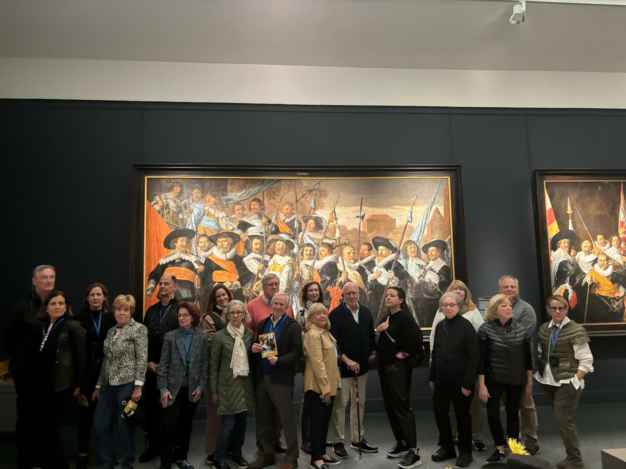 Group of people standing in front of a large painting in an art gallery.