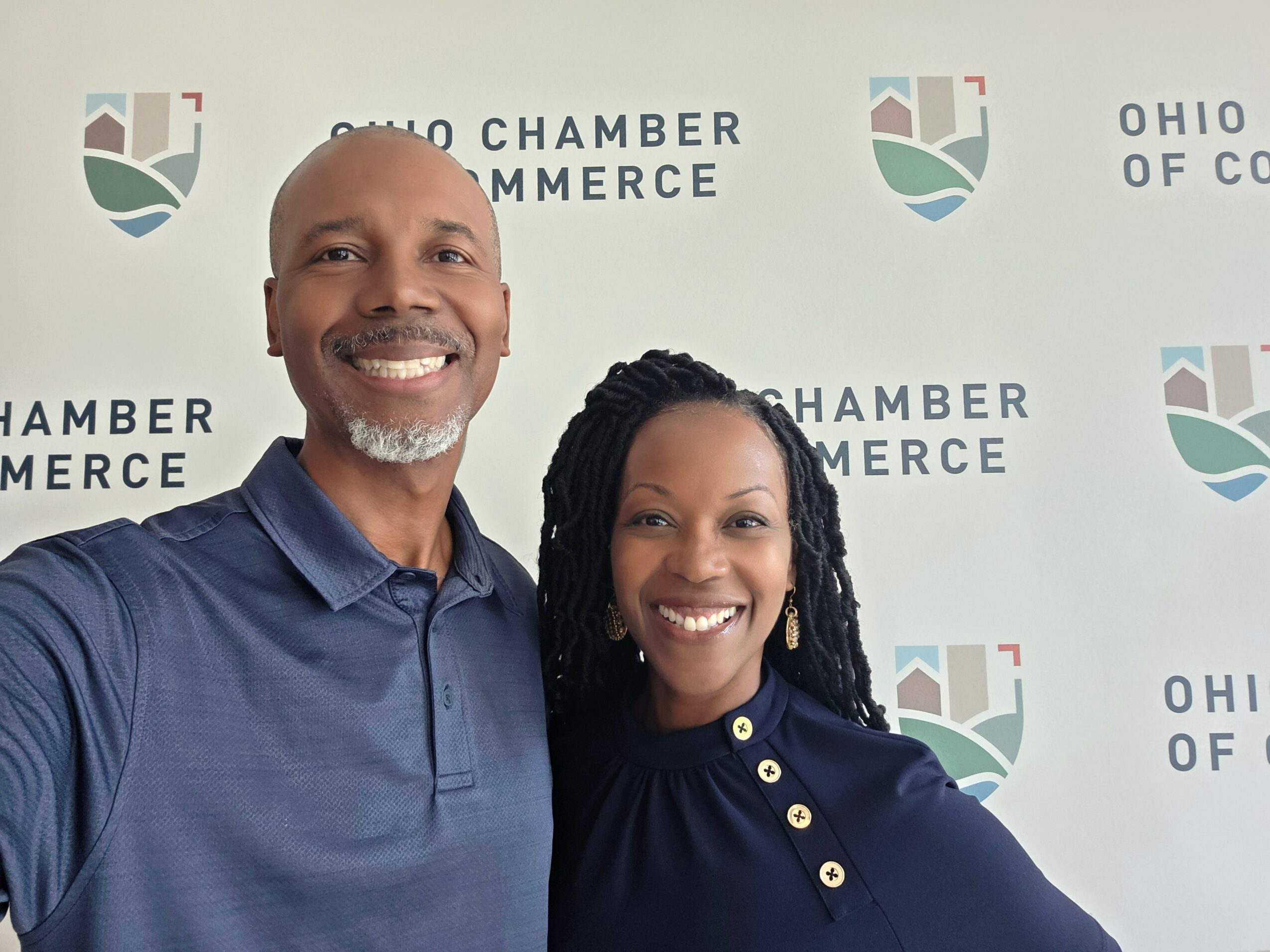 Two smiling people standing in front of a Ohio Chamber of Commerce backdrop.