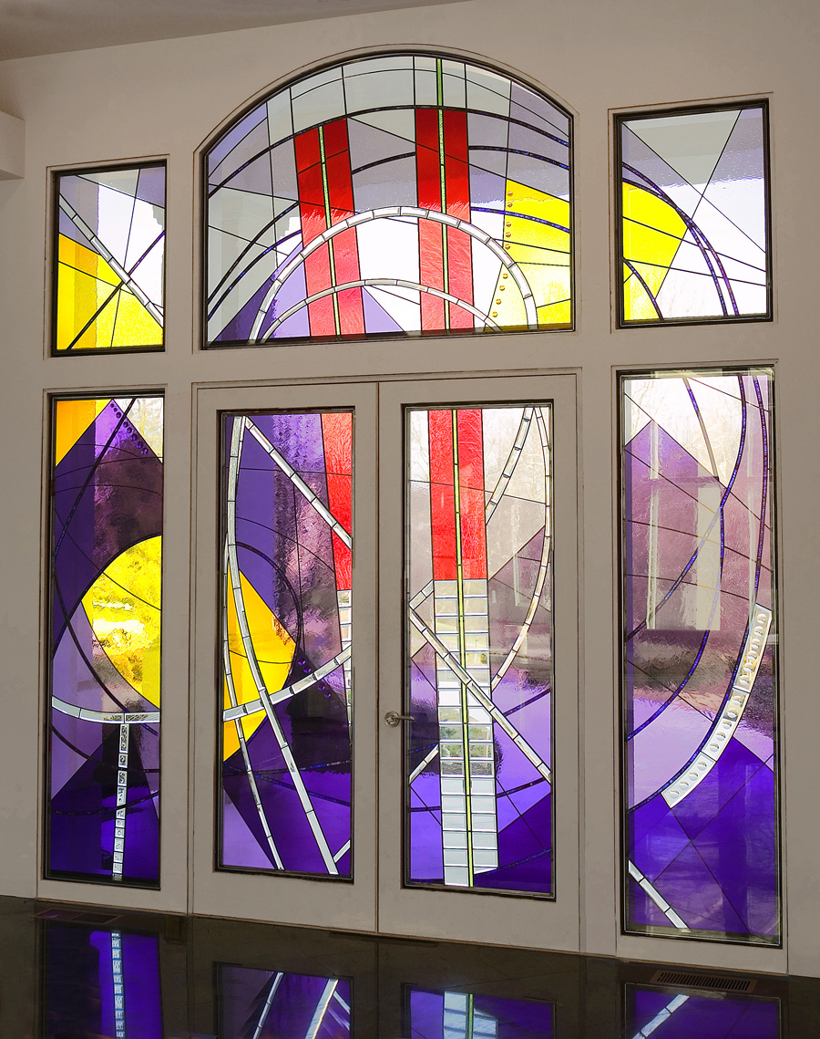 Colorful stained glass window with geometric shapes and vibrant colors including yellow, purple, red, and white.