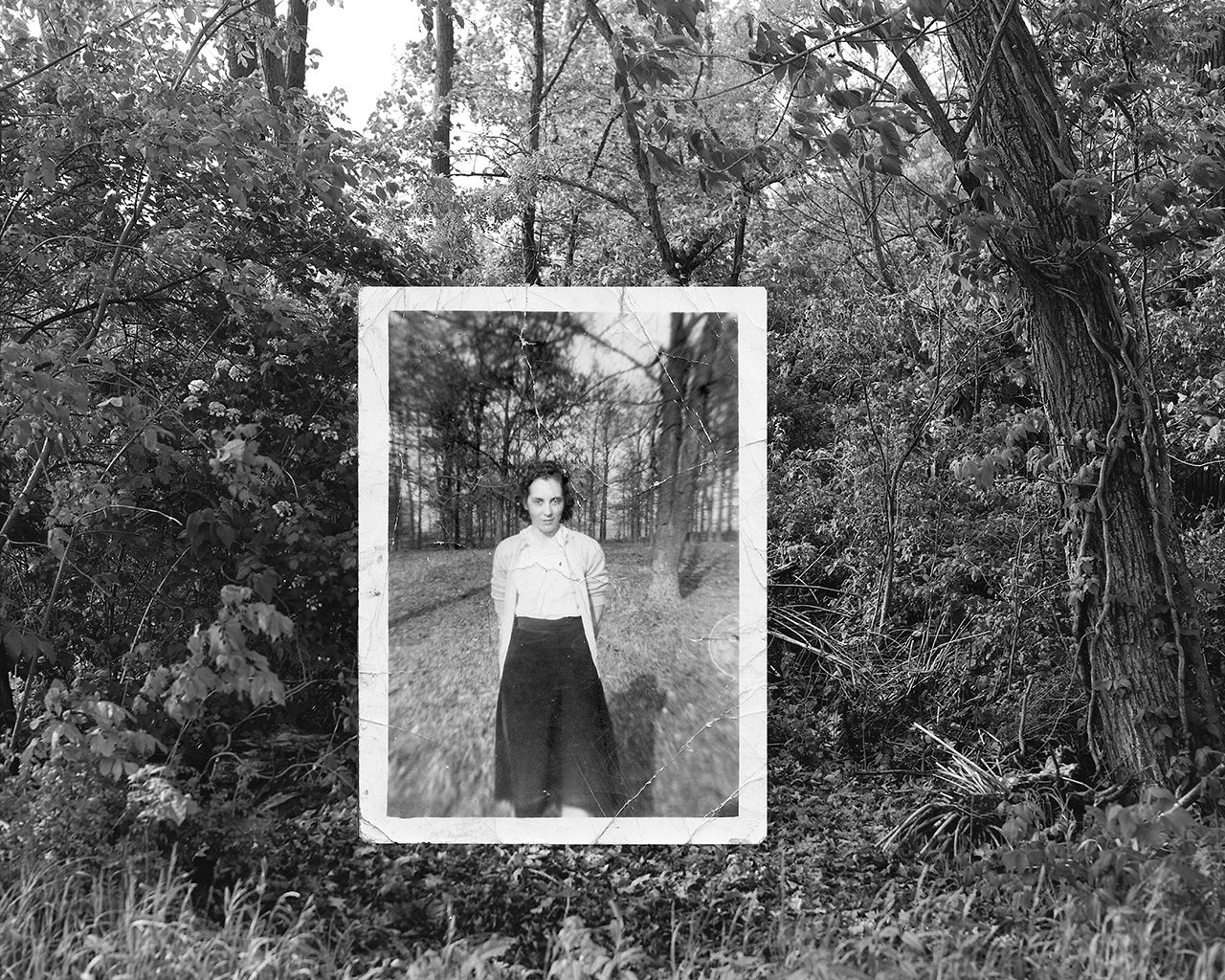 Black and white photo of a woman standing outdoors, framed within a white border, surrounded by trees and foliage.