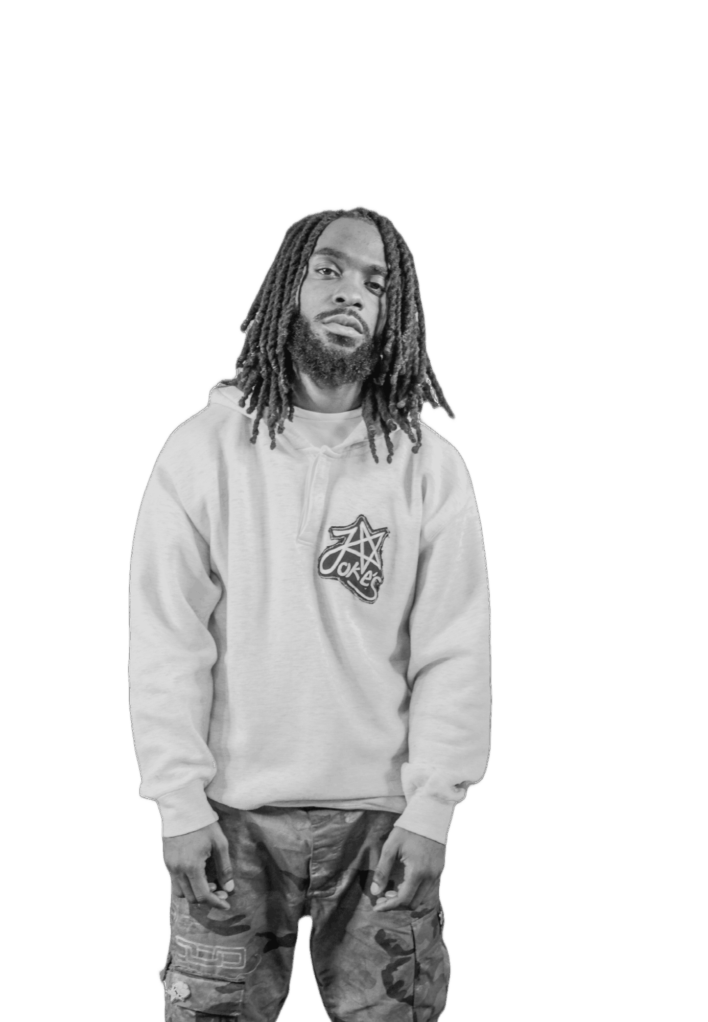 Young man with dreadlocks wearing a hoodie and jeans, standing against a black background.