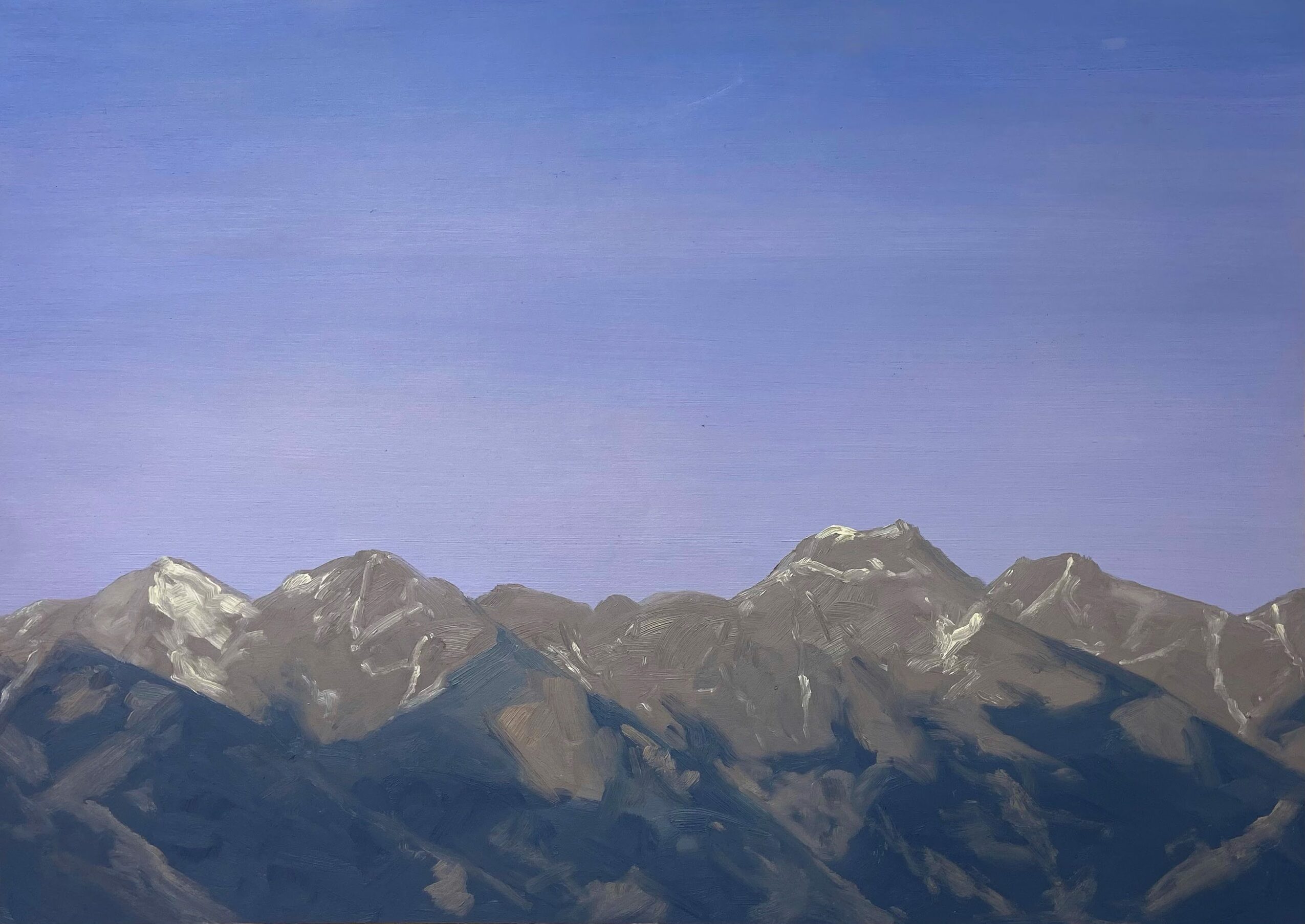 Mountain range with snow-capped peaks under a clear blue sky.