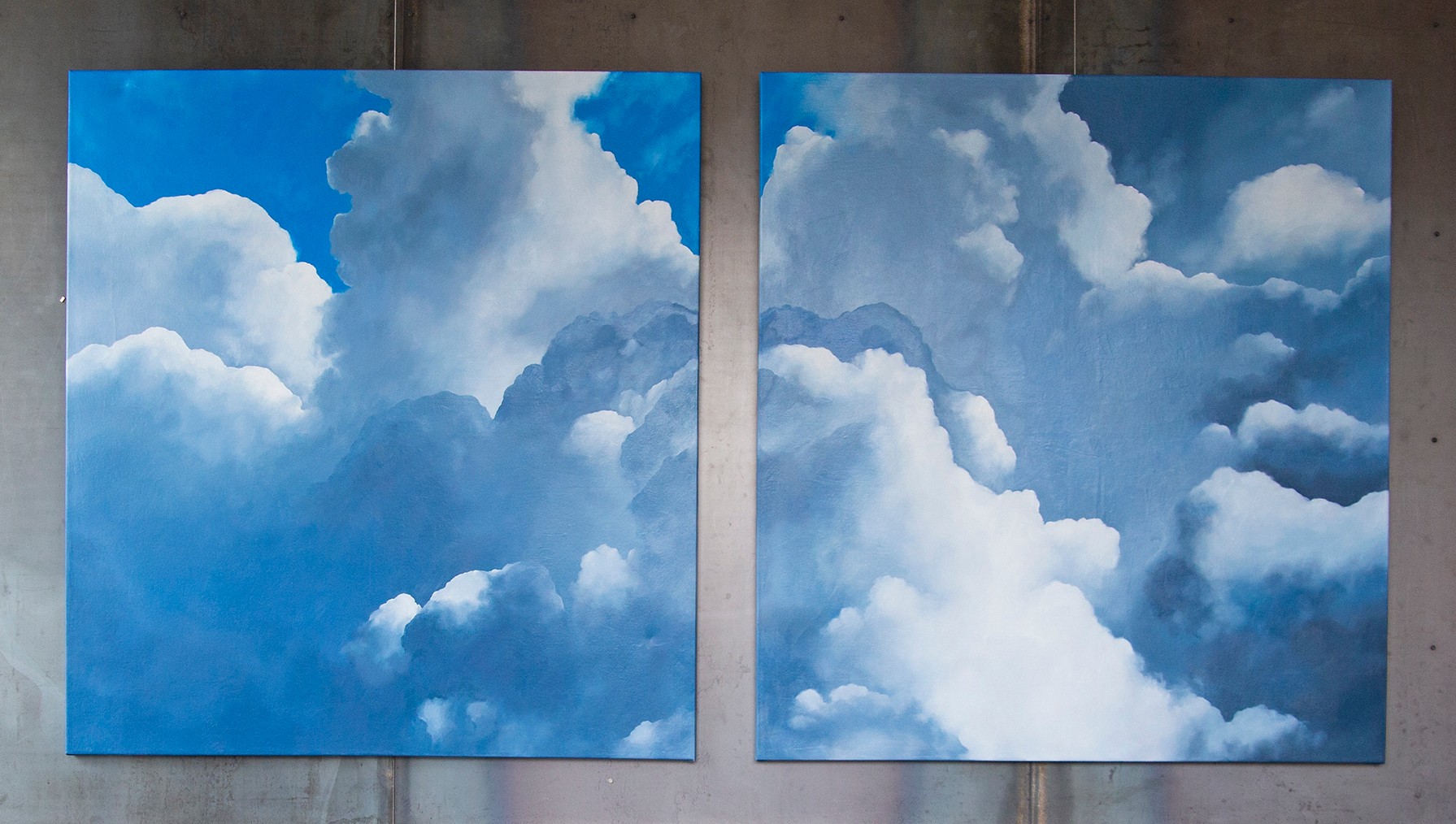 Two paintings of cloudy sky scenes, with white and gray clouds against blue backgrounds, placed side by side.