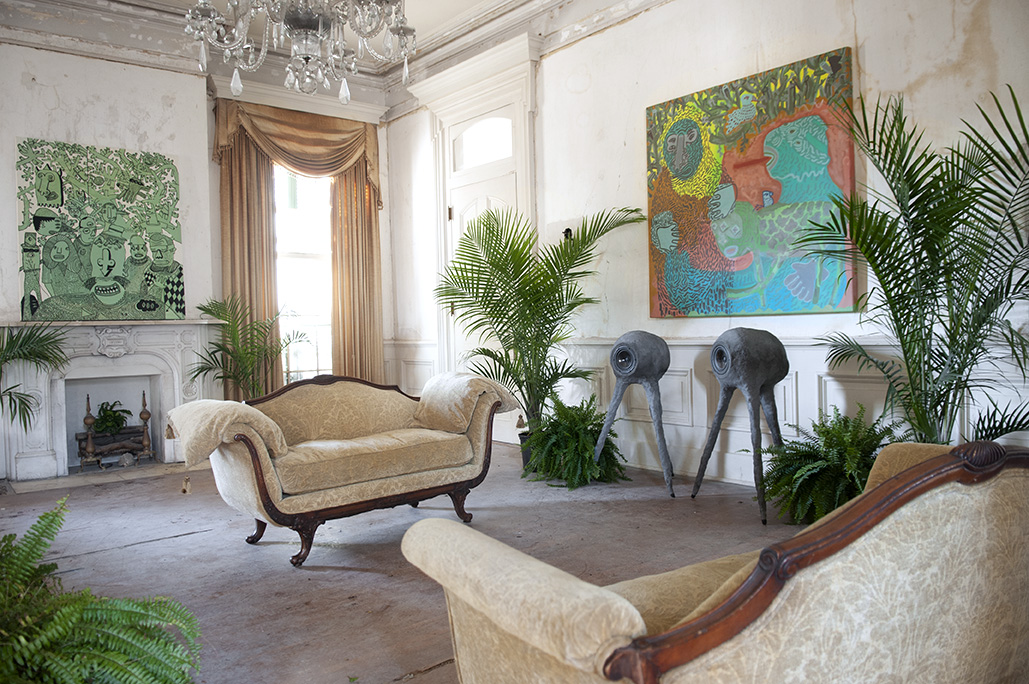 Elegant living room with vintage sofa, large windows, colorful paintings, and indoor plants.