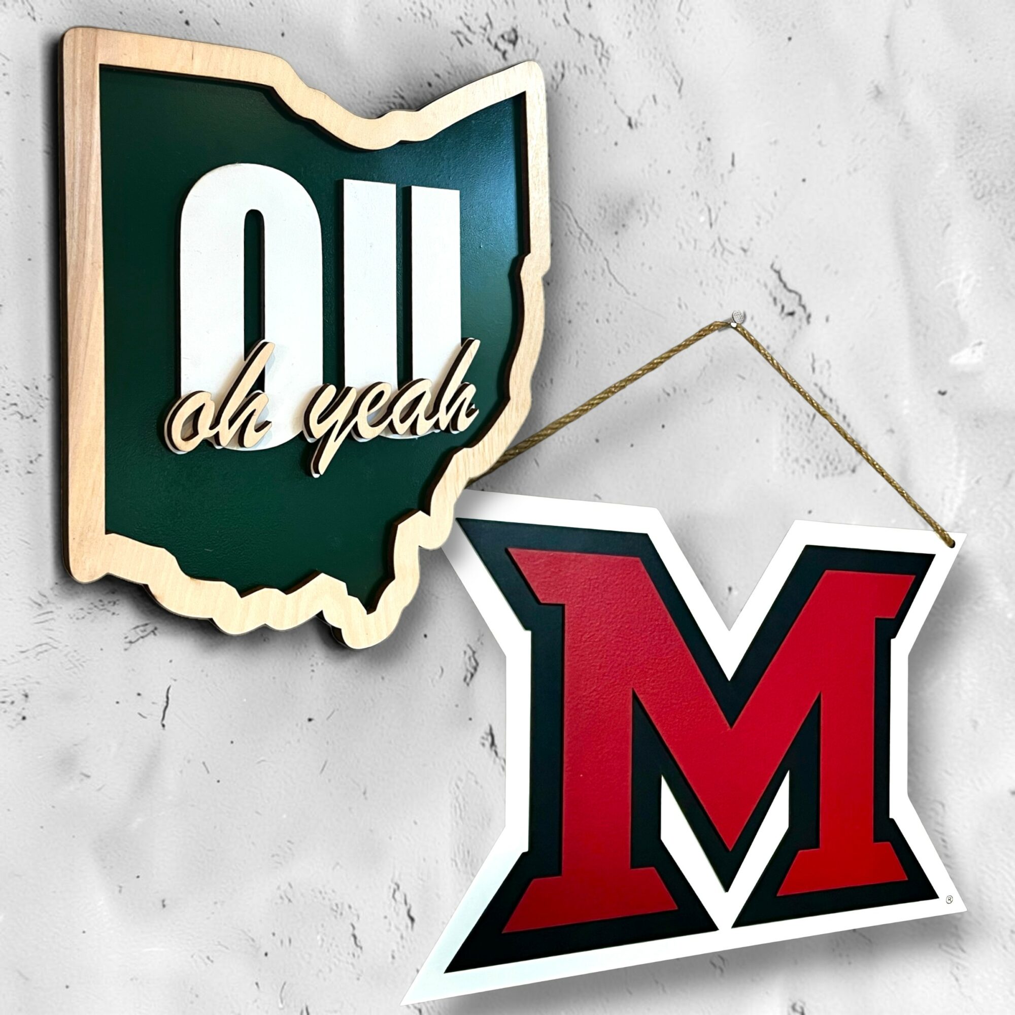 Decorative sign with Ohio shape and text, and a red letter M hanging on a wall.