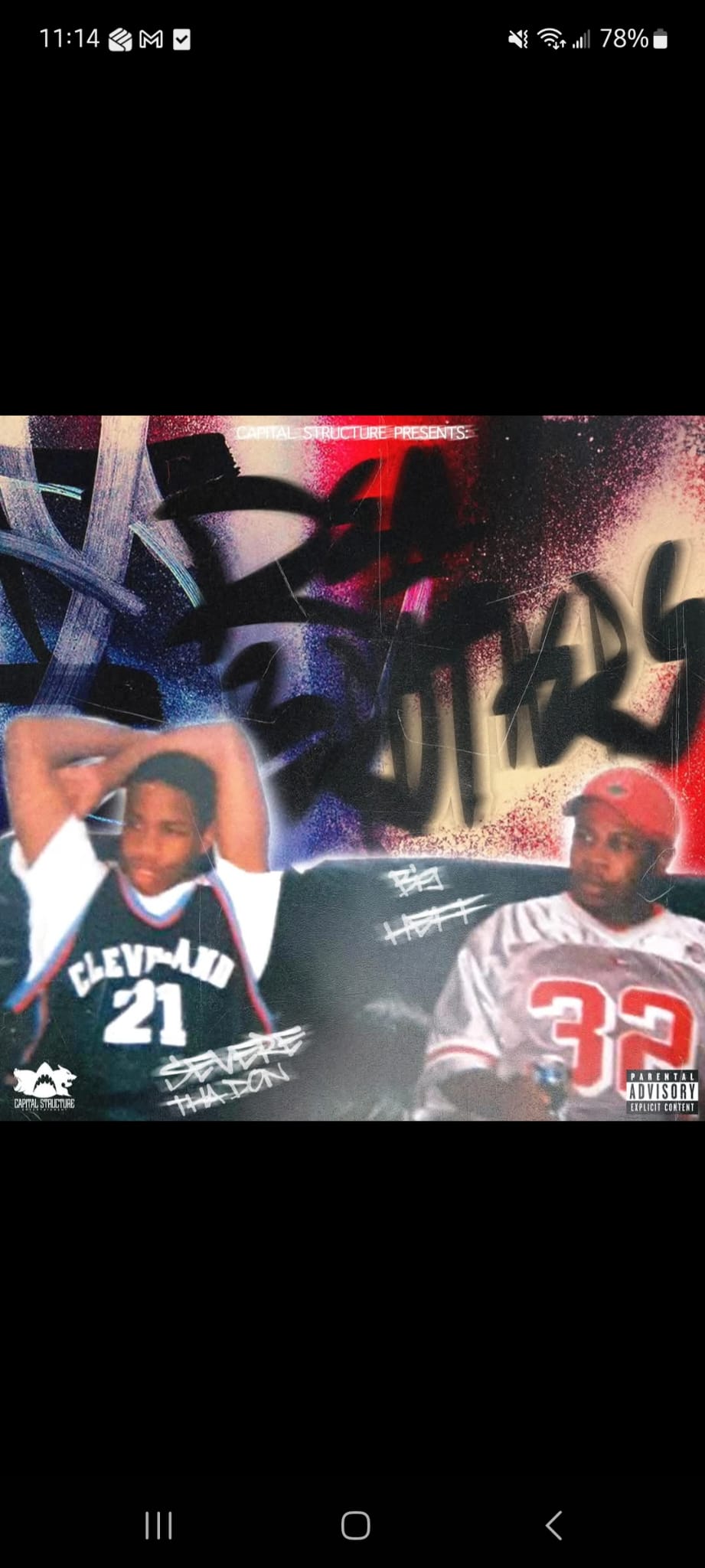 Two young boys in front of graffiti art, one wearing a Cleveland jersey and the other a red cap, both smiling.