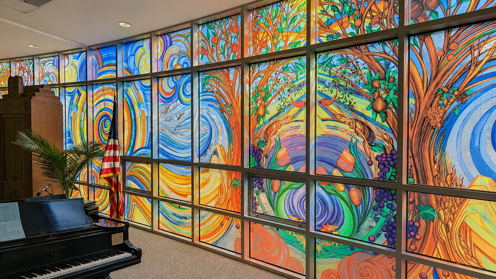 Colorful abstract mural with swirling patterns and vibrant colors on a large wall, with a piano and American flag nearby.