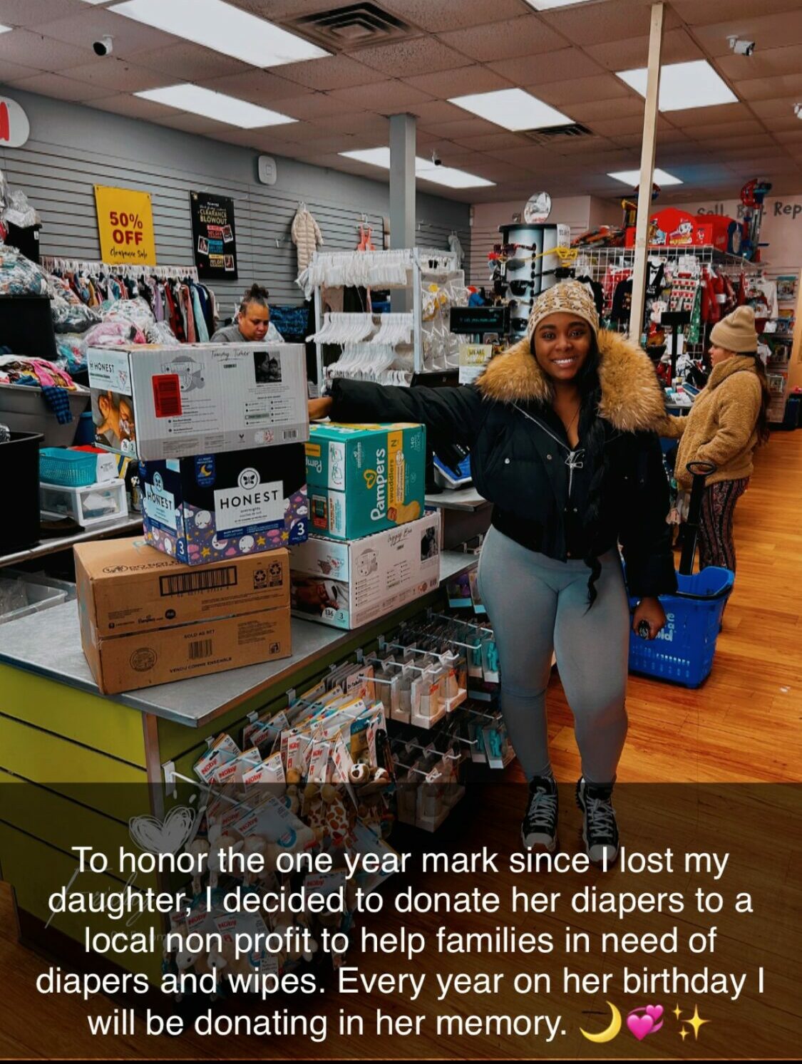 Person with curly hair in a store aisle, surrounded by boxes and products, smiling at the camera.