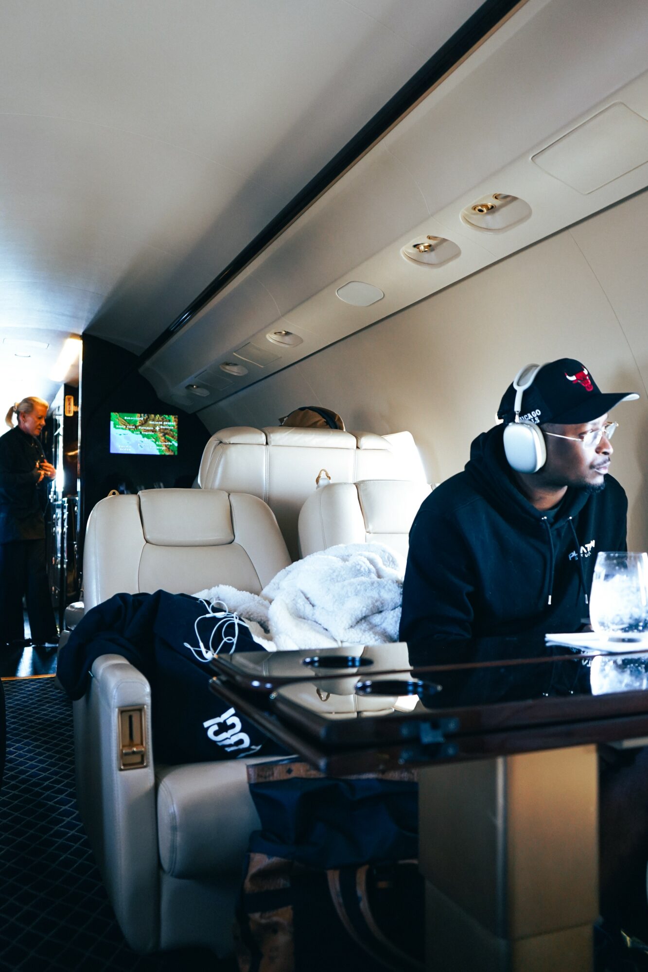 Passenger seated with headphones, window, and overhead controls visible inside aircraft cabin.