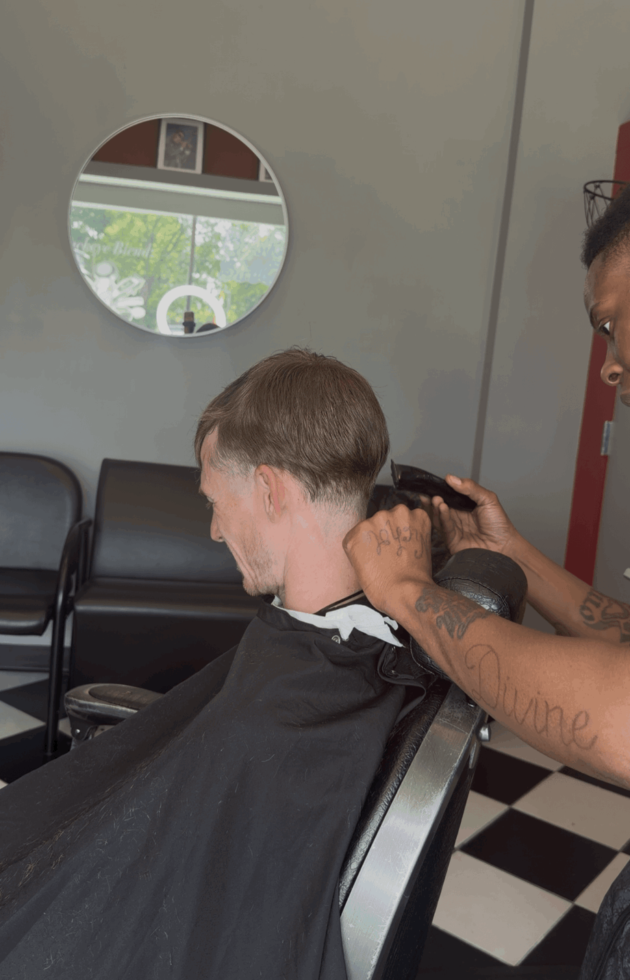 Child getting a haircut in a salon, seated in a chair with a cape, mirror on the wall, and a stylist working.
