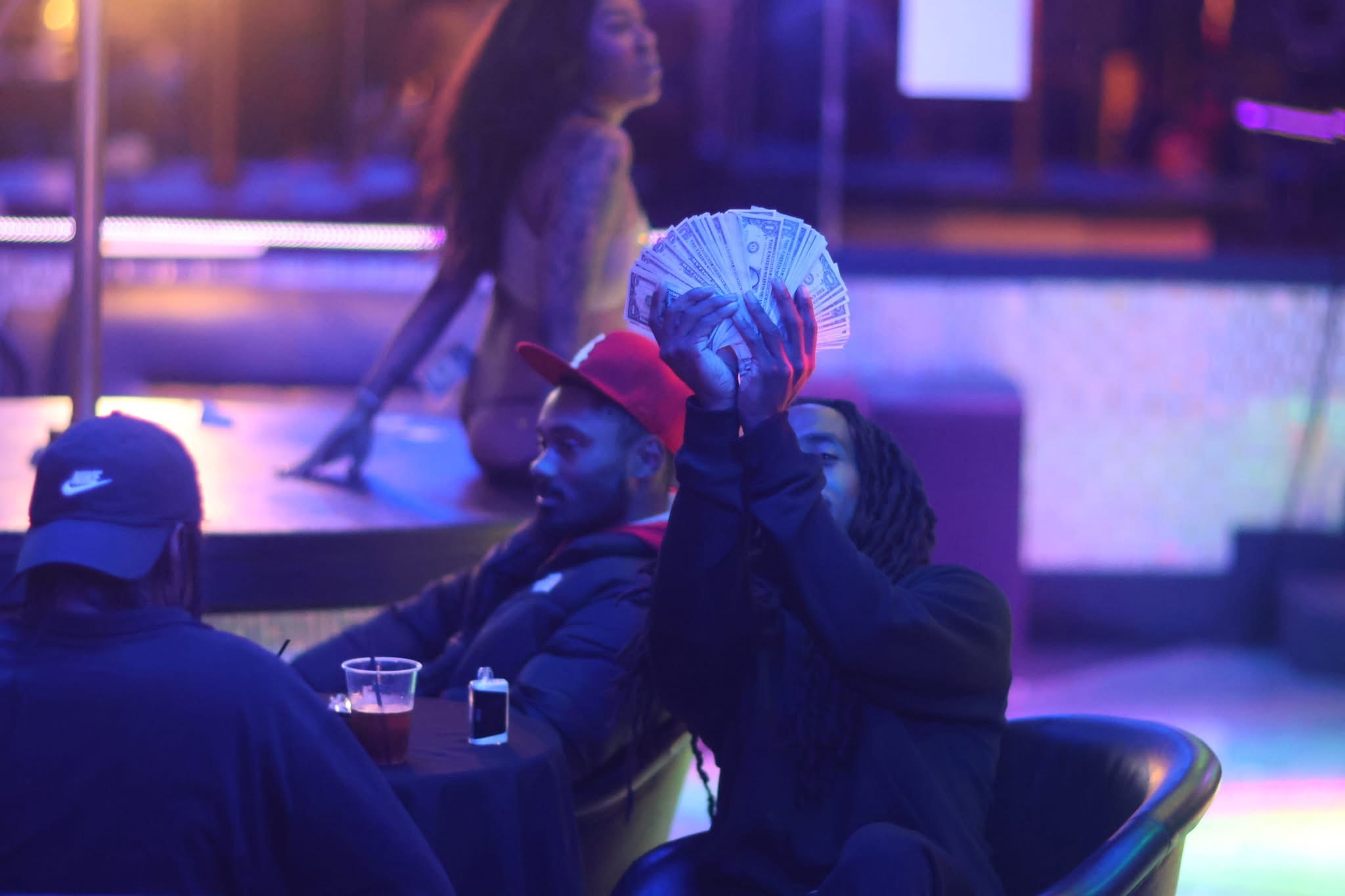 Person holding a blue and white striped bag over their head in a dimly lit setting with people in the background.