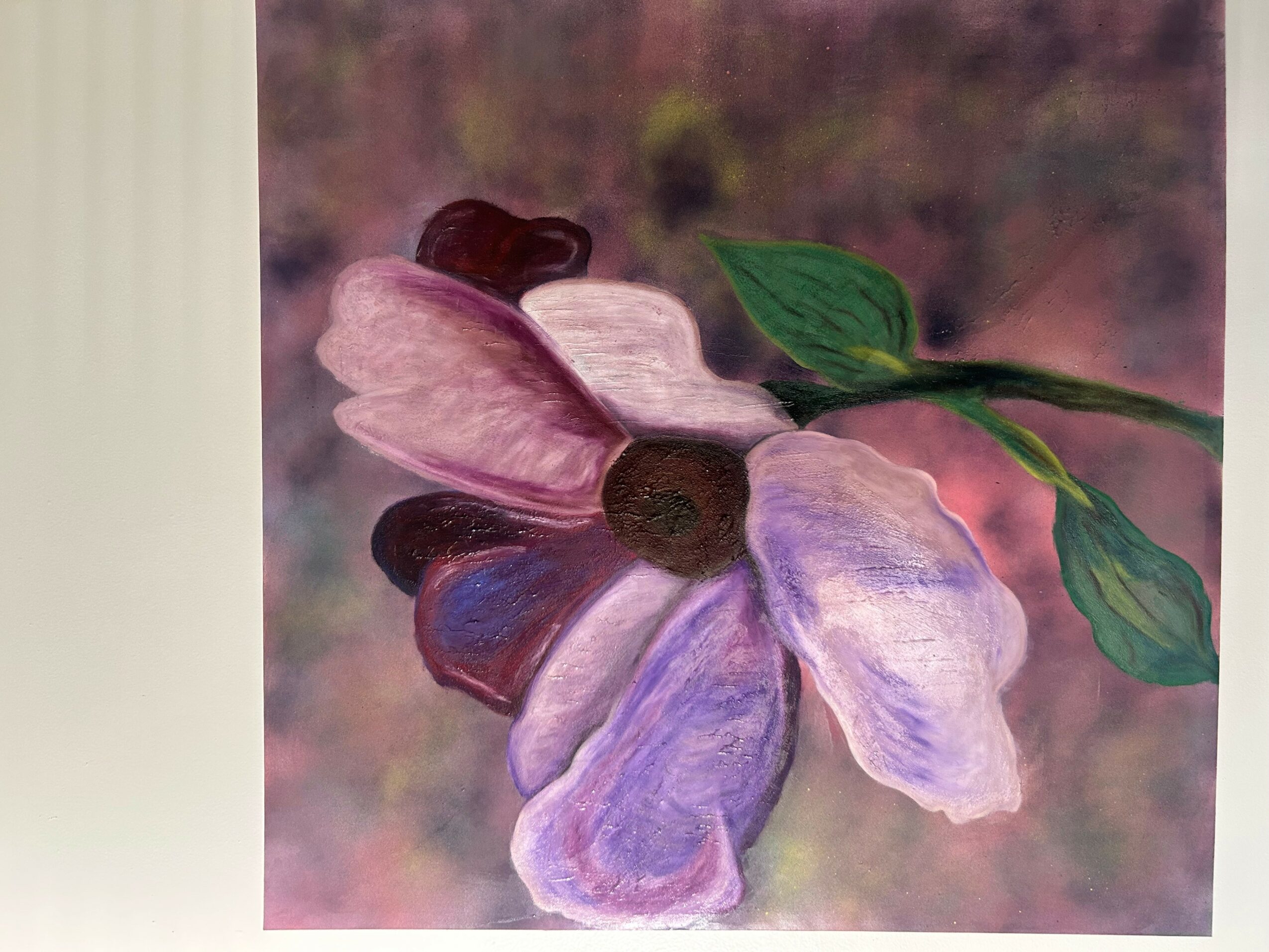 Close-up of a flower with pink, purple, and blue petals and green leaves, against a blurred background.