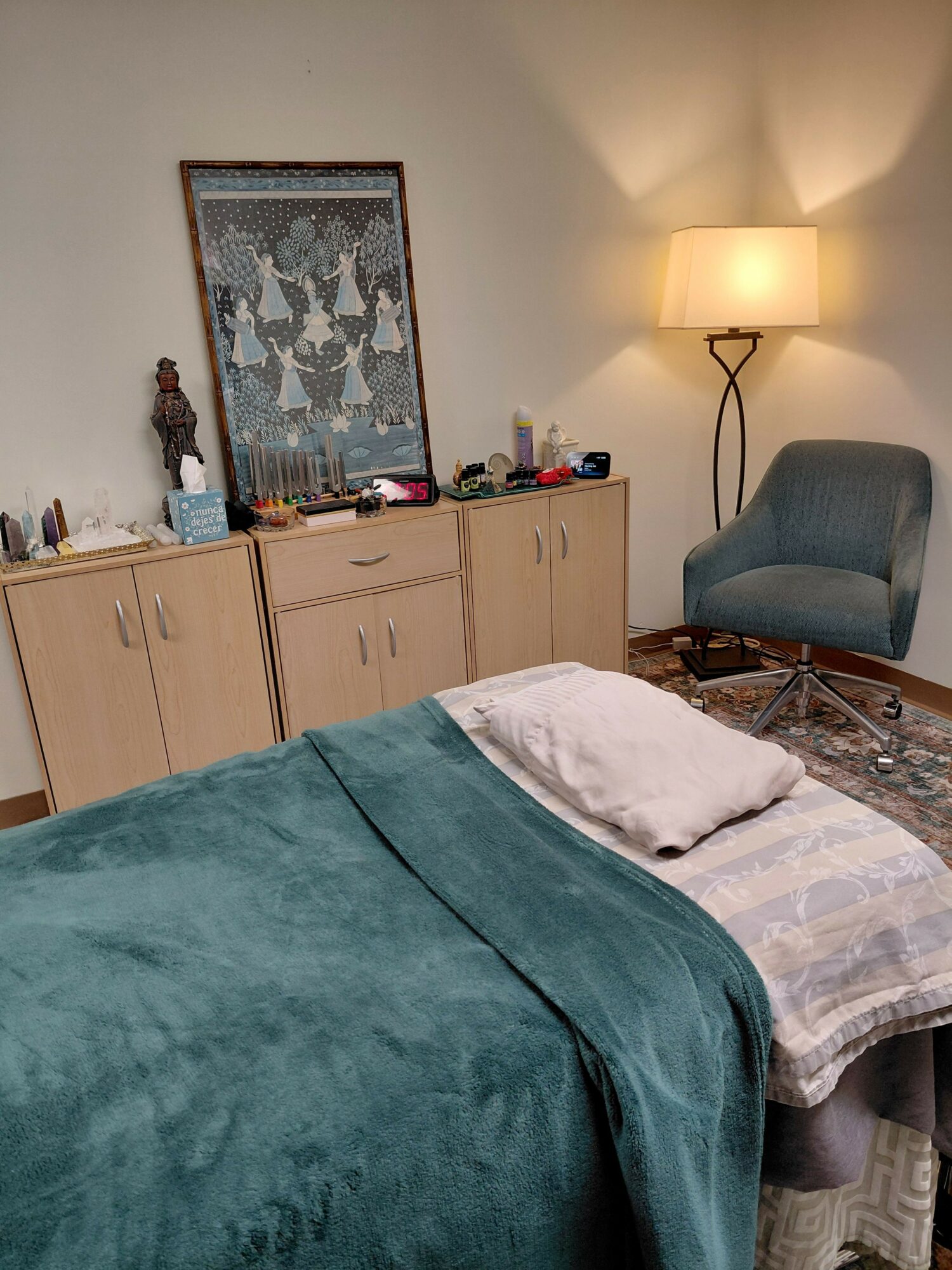 Bedroom with a bed, a wooden cabinet, a lamp, and a wall decoration, viewed from the side.