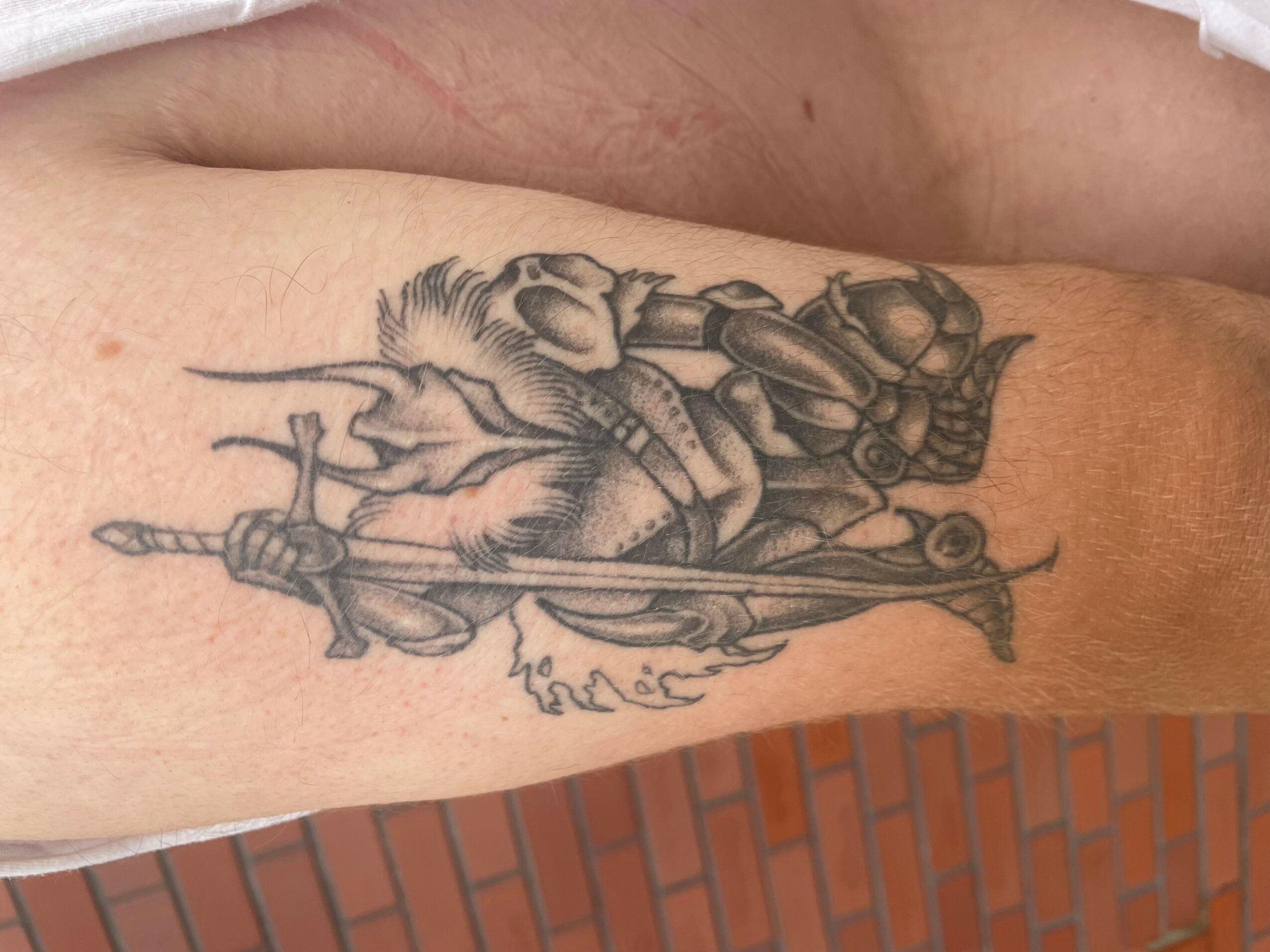 Tattoo of a knight in armor riding a horse, holding a spear, on a person's arm.