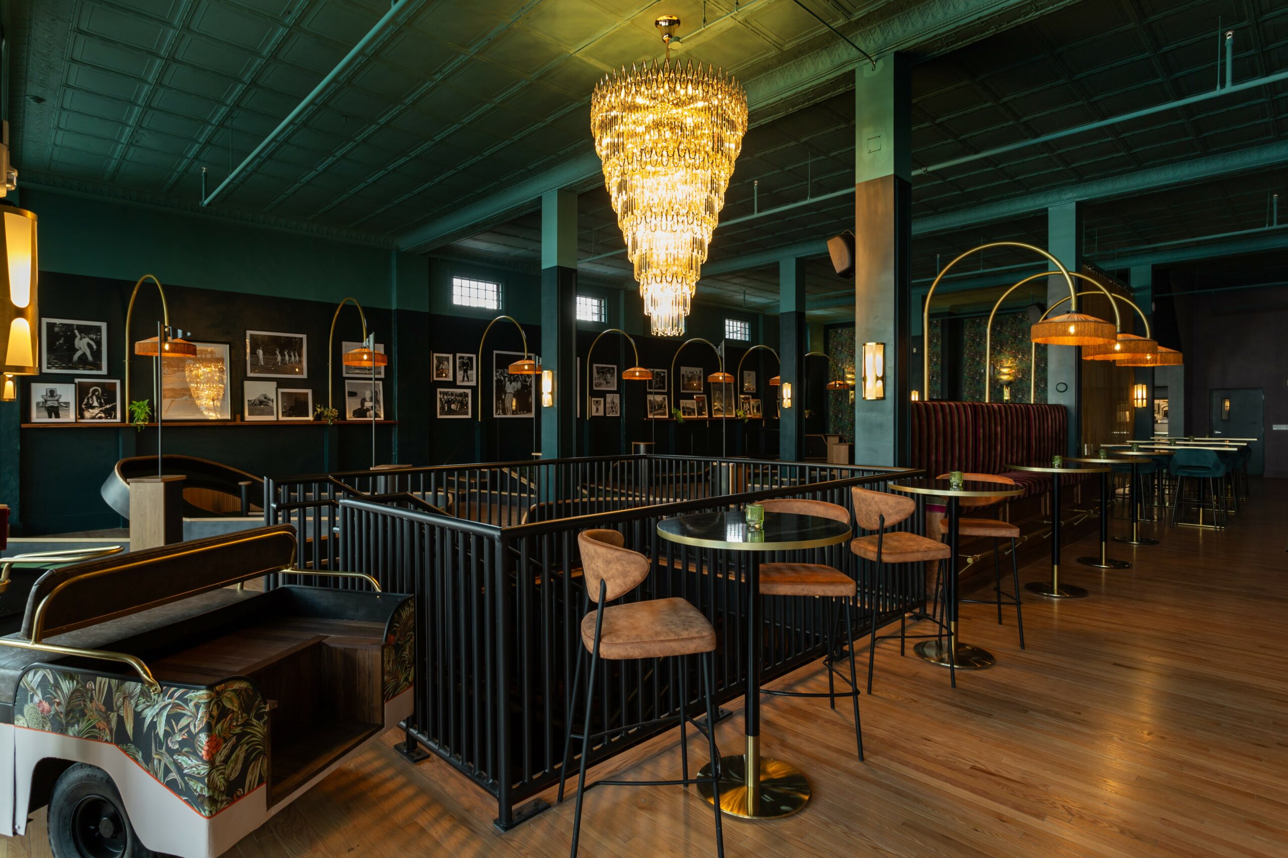 Elegant restaurant interior with chandelier, tables, chairs, and wall art, featuring a dark color scheme and warm lighting.