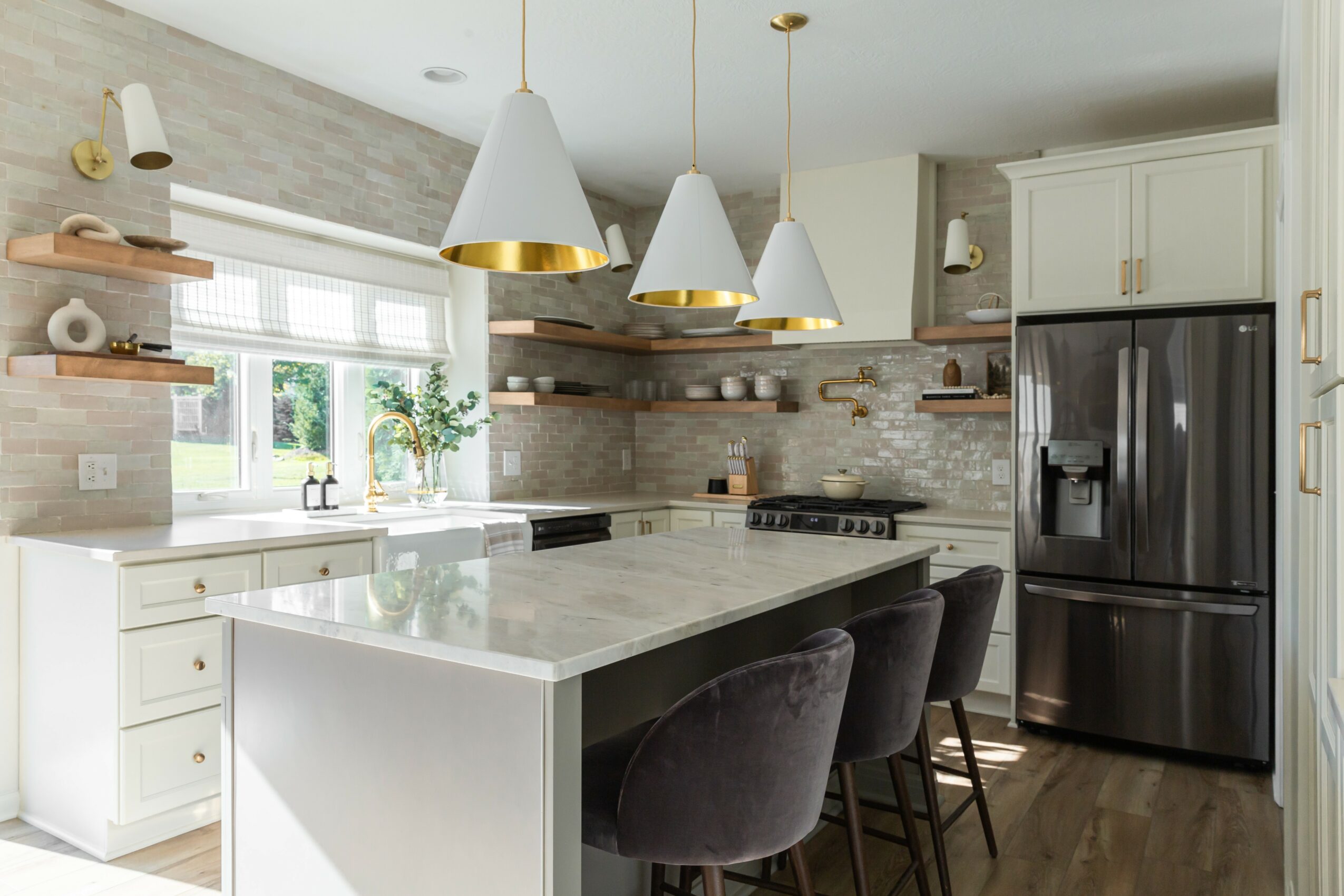 Modern kitchen with white cabinets, marble island, black refrigerator, and pendant lights, featuring a window with plants and open shelves.