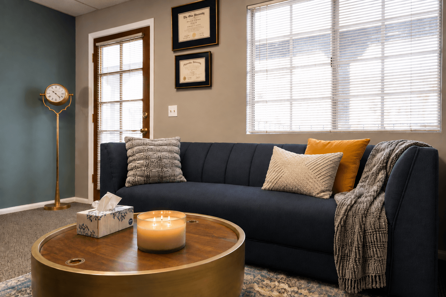 Living room with a dark blue sofa, pillows, a wooden coffee table, and a window with blinds.