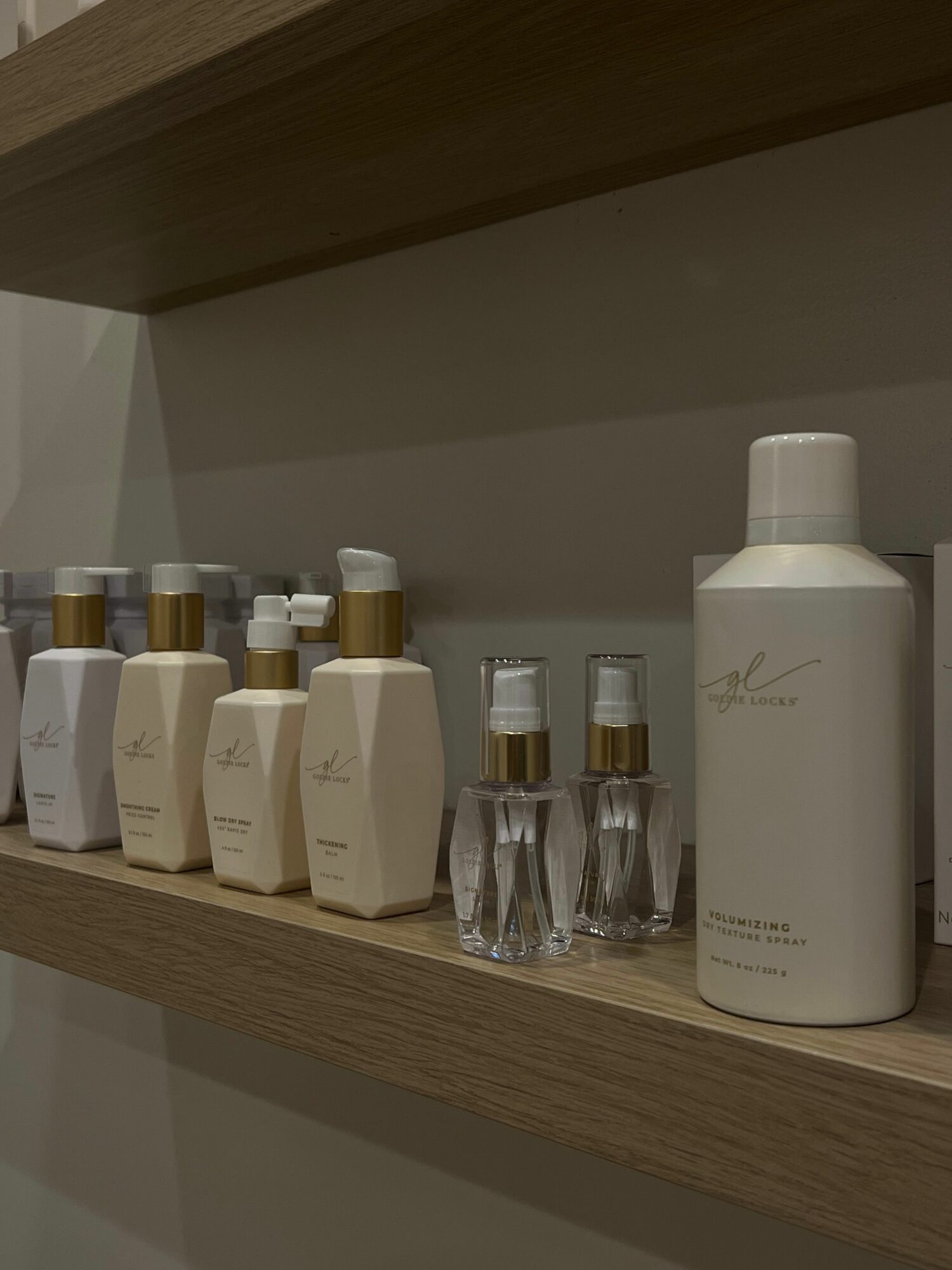 Skincare or cosmetic bottles and jars arranged on a wooden surface, with a large white bottle at the back.