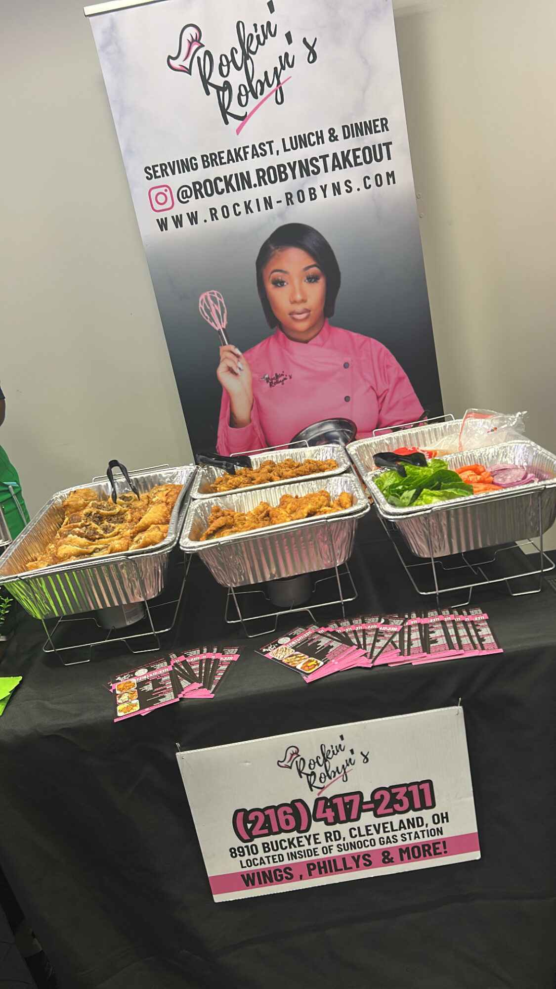 Table with food containers and a promotional banner featuring a woman in a pink shirt holding a fork, with contact information.