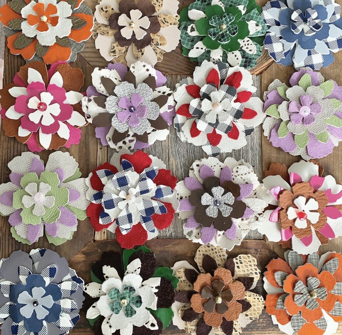 Collection of colorful fabric flower brooches arranged on a wooden surface.