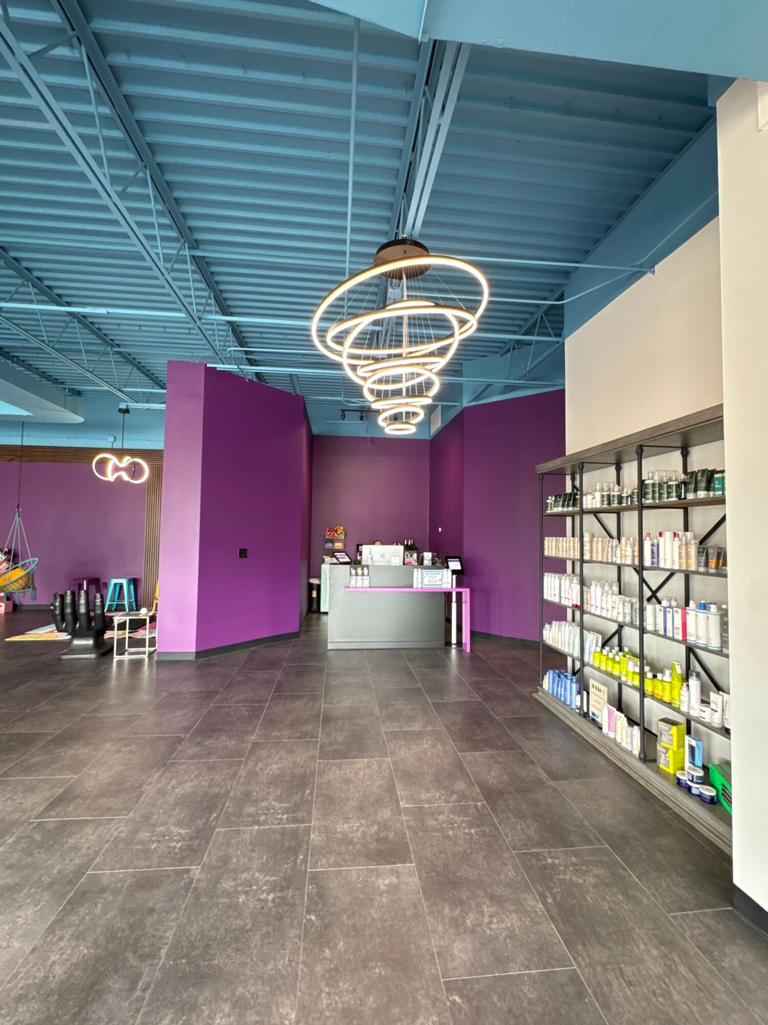 Interior of a modern store with purple and teal walls, display shelves, and a seating area, viewed from the side.