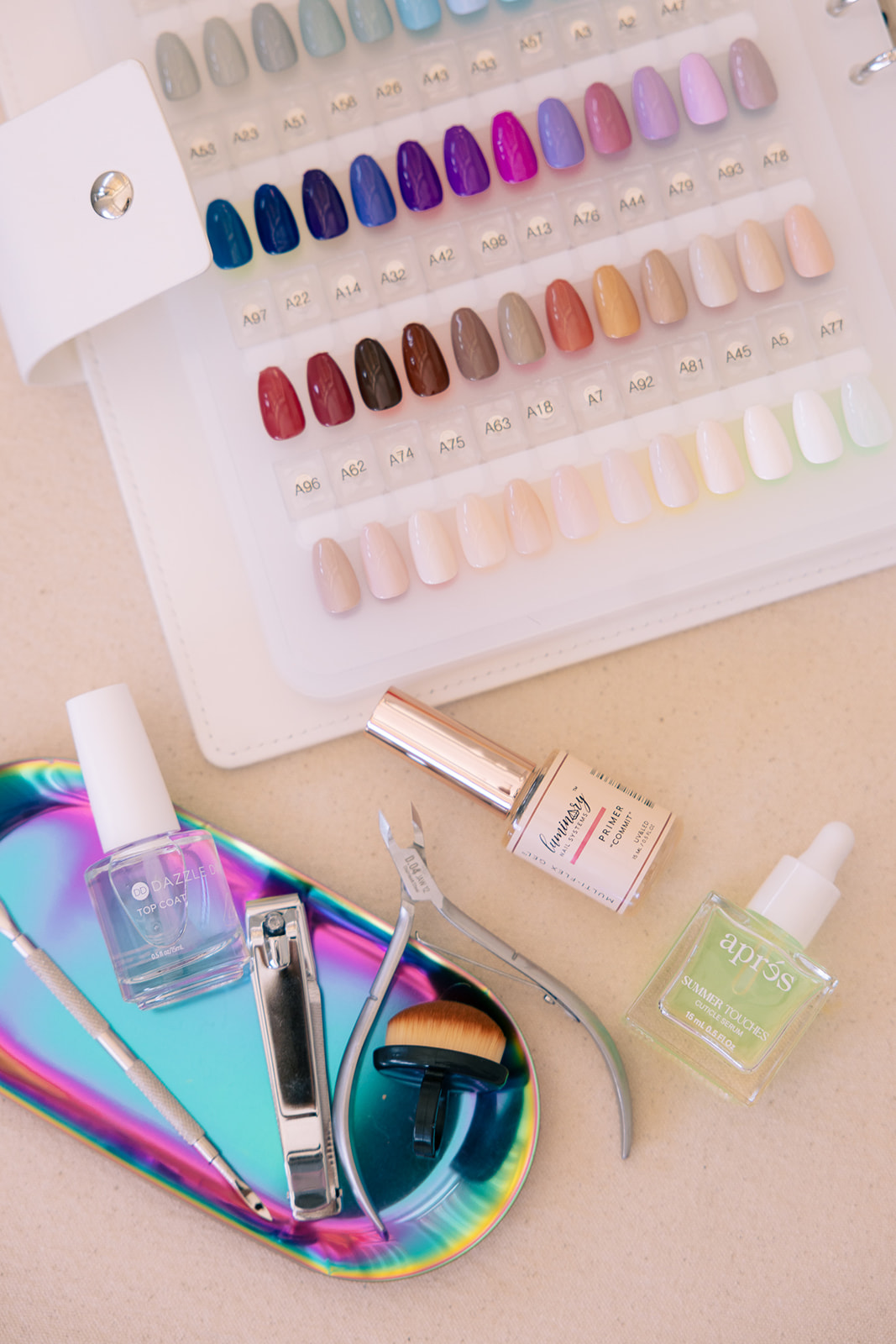 Display of colorful nail polish samples with various shades, along with manicure tools and nail polish bottles on a holographic tray.