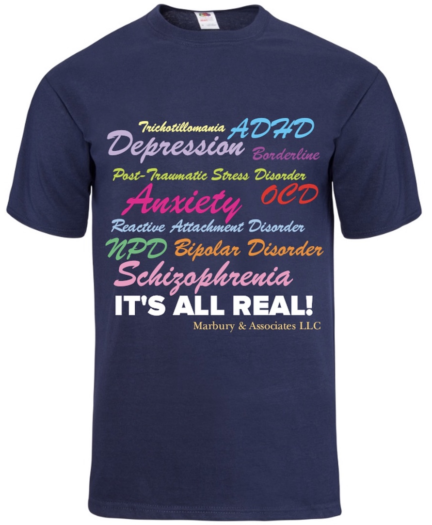 Navy T-shirt with colorful words related to mental health conditions, including depression, anxiety, ADHD, OCD, and schizophrenia, and the phrase 'IT'S ALL REAL!'.