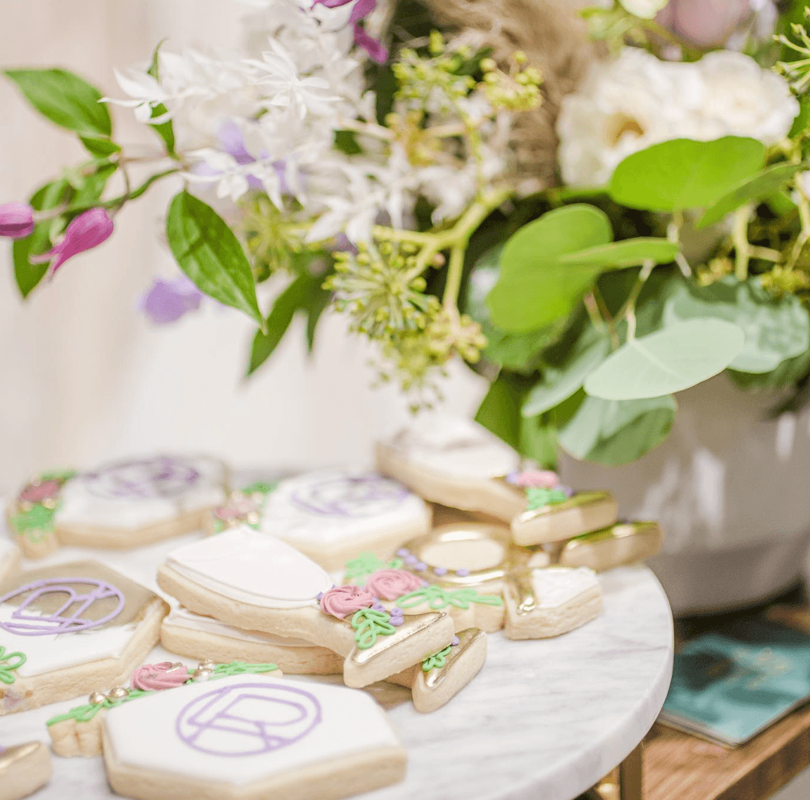 Decorative cookies with peace symbols and floral designs on a white surface, with a bouquet of flowers in the background.