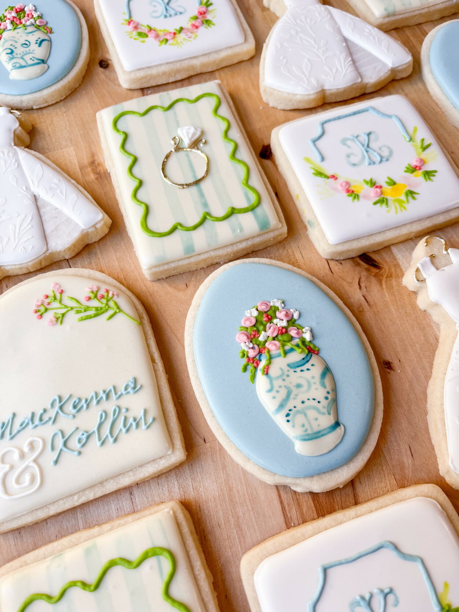Decorative cookies with floral and ring designs, some with white icing, arranged on a wooden surface.